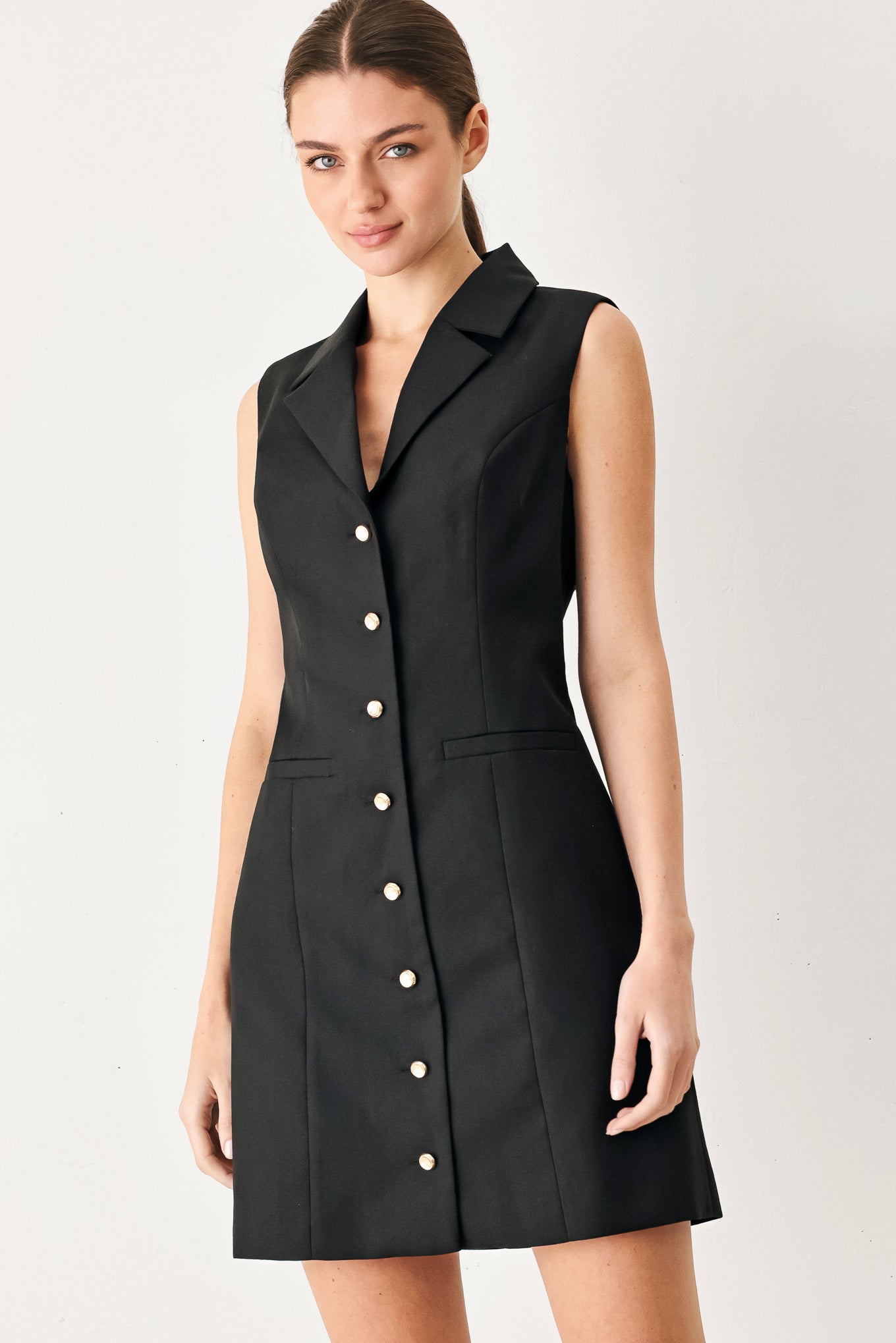 Woman wearing a black sleeveless mini dress featuring blazer collar and front button down | FREEMARKET