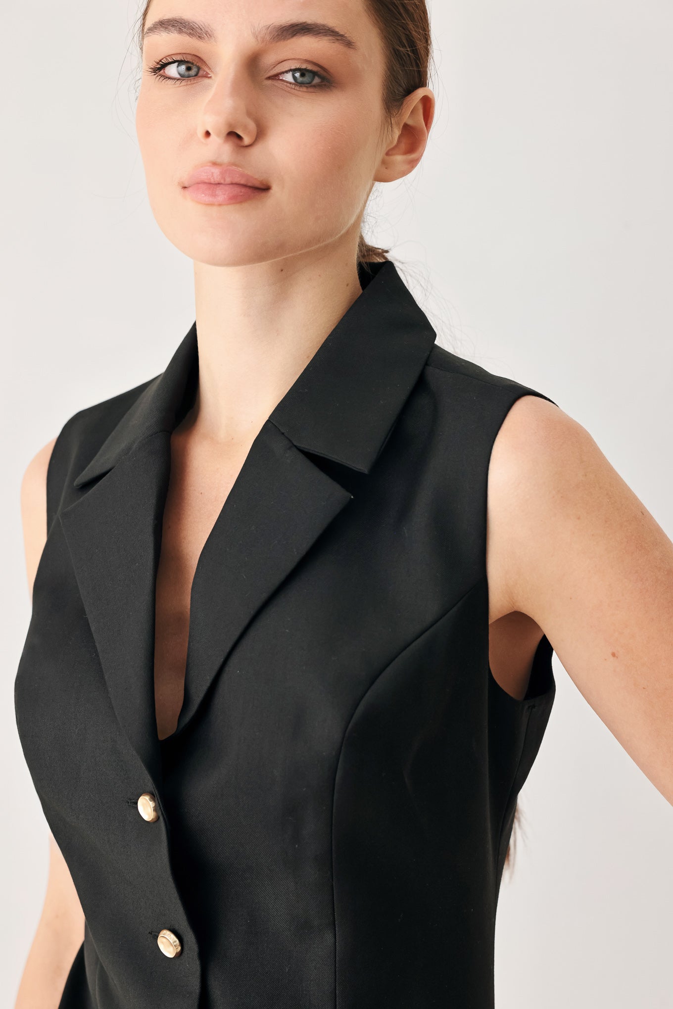 Woman wearing a black sleeveless mini dress featuring blazer collar and front button down | FREEMARKET