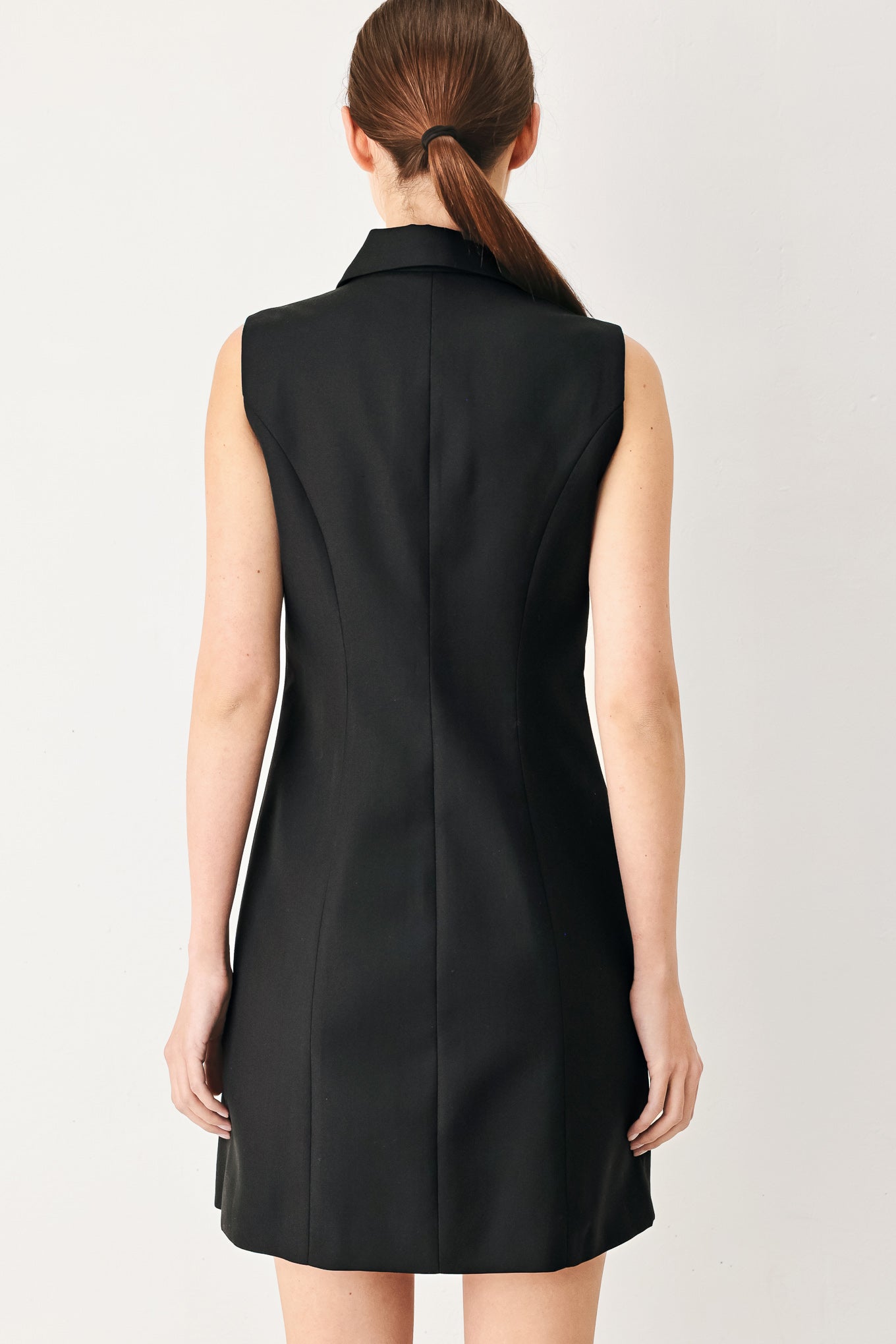 Woman wearing a black sleeveless mini dress featuring blazer collar and front button down | FREEMARKET