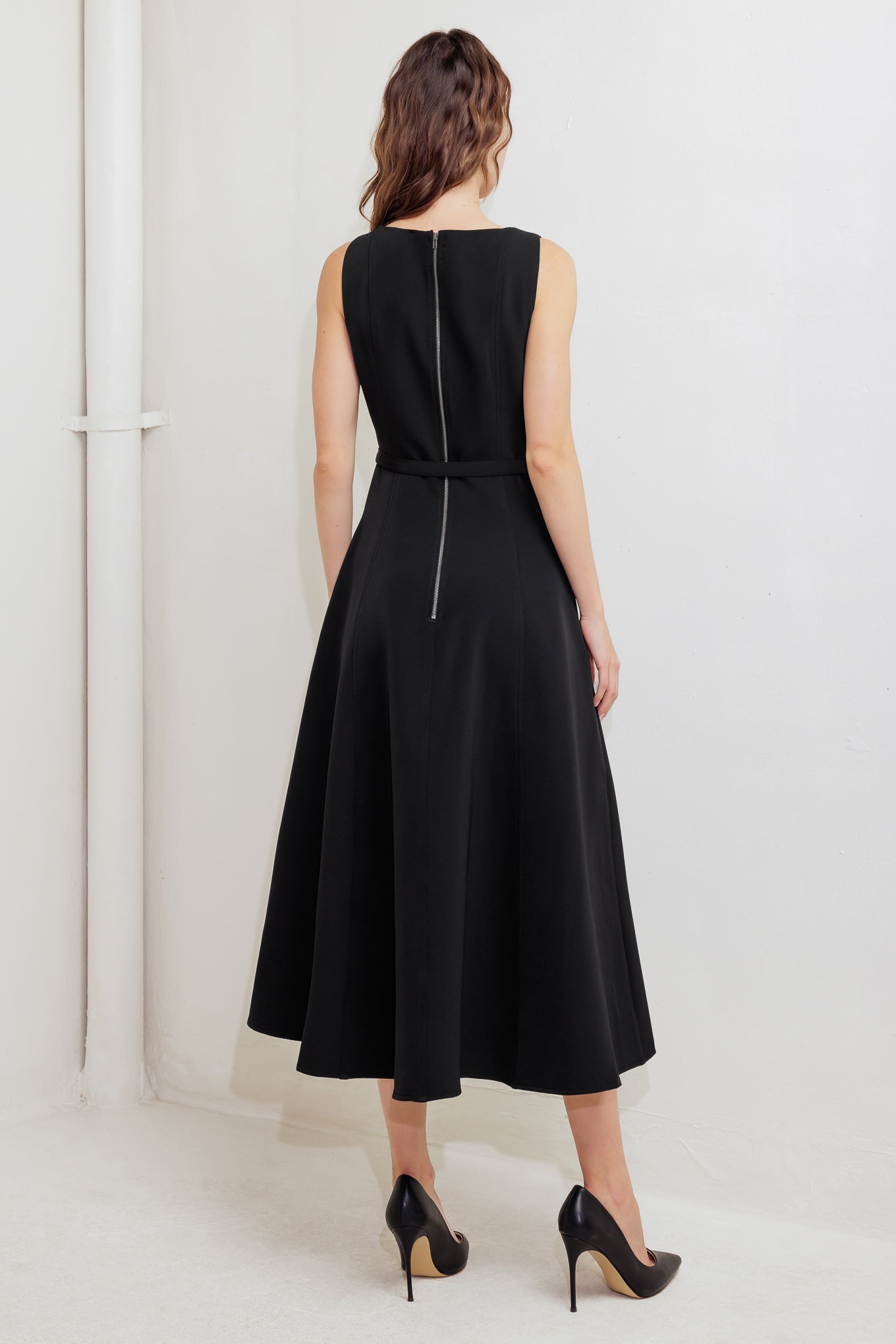 A solid woven midi dress featuring U neckline, sleeveless, self belt, circle skirt and back zipper closure