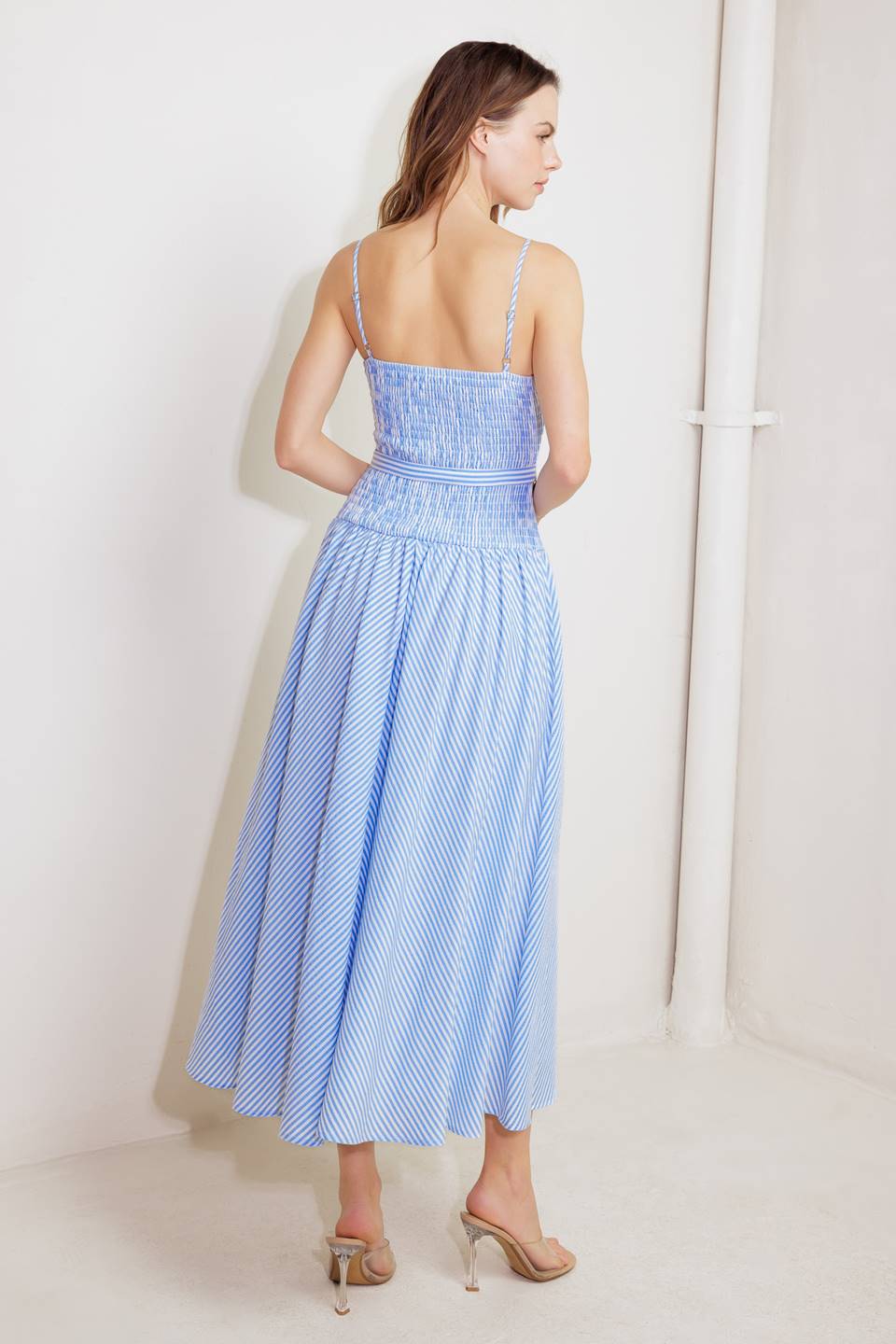 A striped woven midi dress featuring V neckline, straps, smocked bodice self belt and full skirt