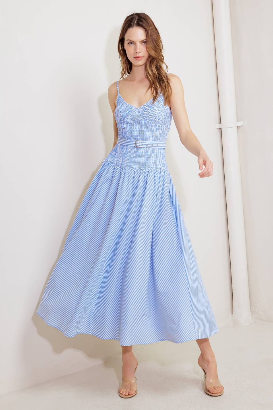 A striped woven midi dress featuring V neckline, straps, smocked bodice self belt and full skirt