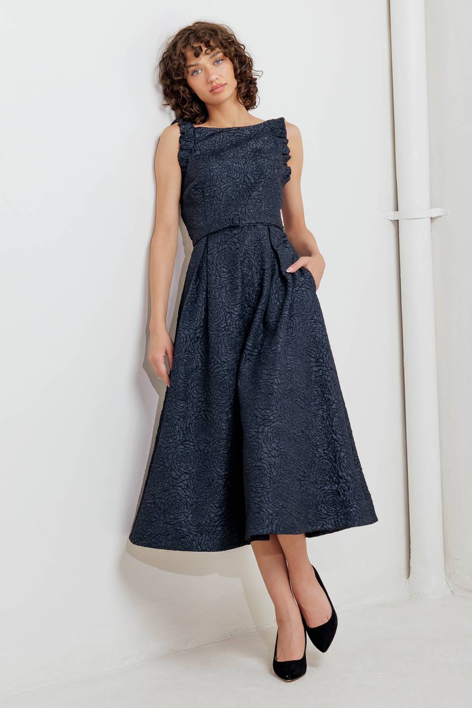 A texture woven midi dress featuring wide neckline, sleeveless with ruffled edge, self belt, full skirt low back with zipper closure