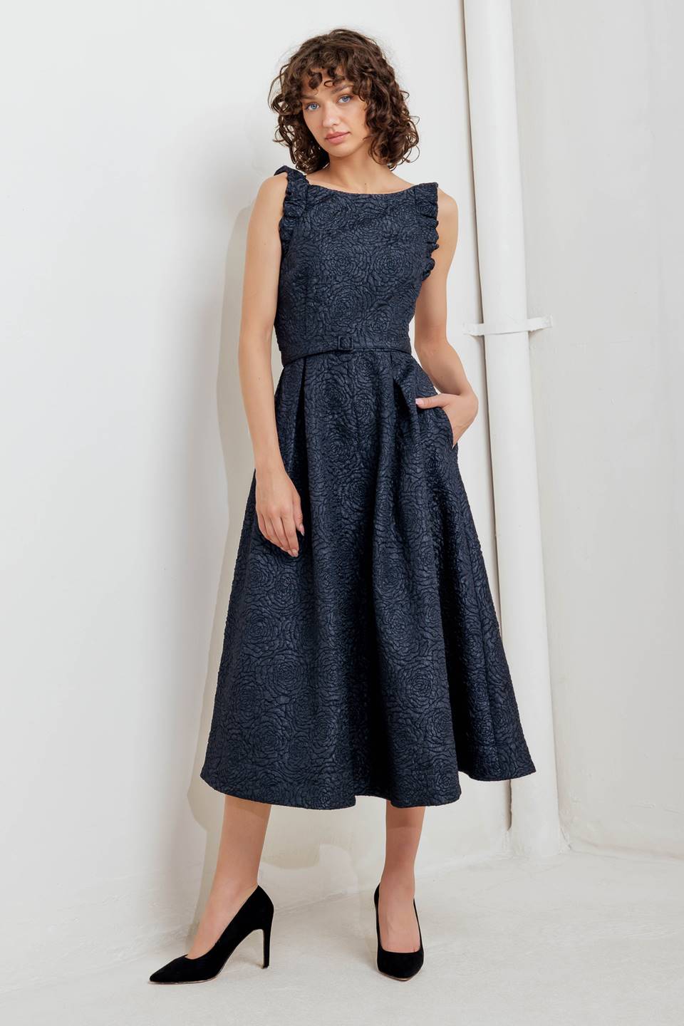 A texture woven midi dress featuring wide neckline, sleeveless with ruffled edge, self belt, full skirt low back with zipper closure