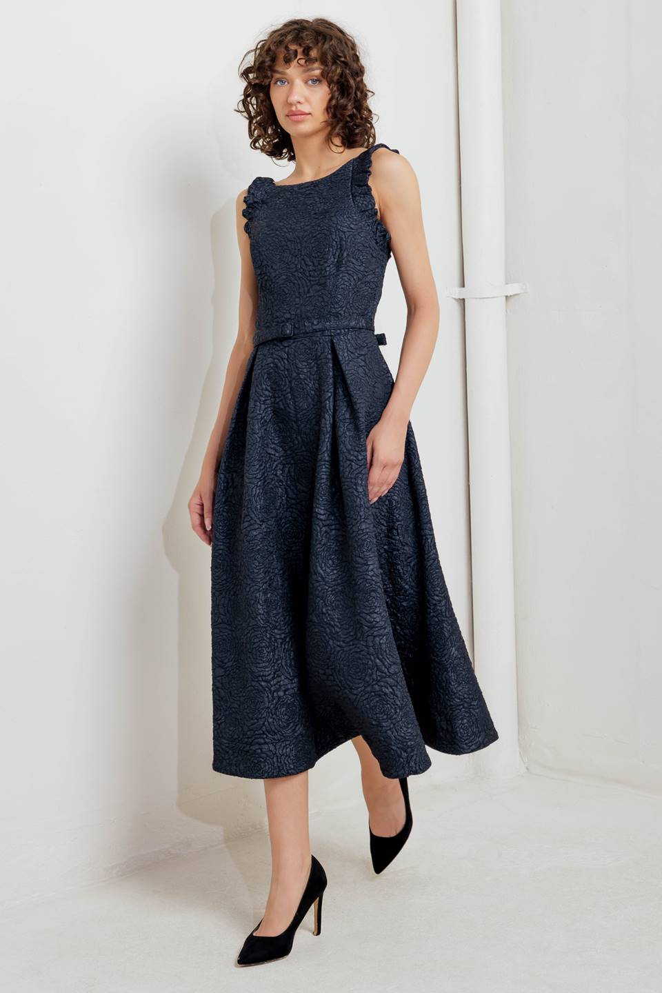 A texture woven midi dress featuring wide neckline, sleeveless with ruffled edge, self belt, full skirt low back with zipper closure