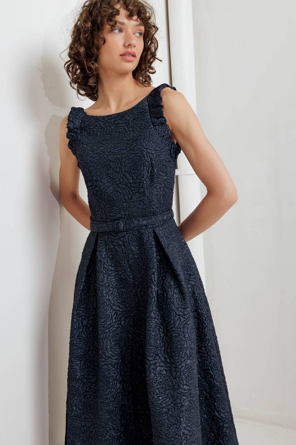 A texture woven midi dress featuring wide neckline, sleeveless with ruffled edge, self belt, full skirt low back with zipper closure