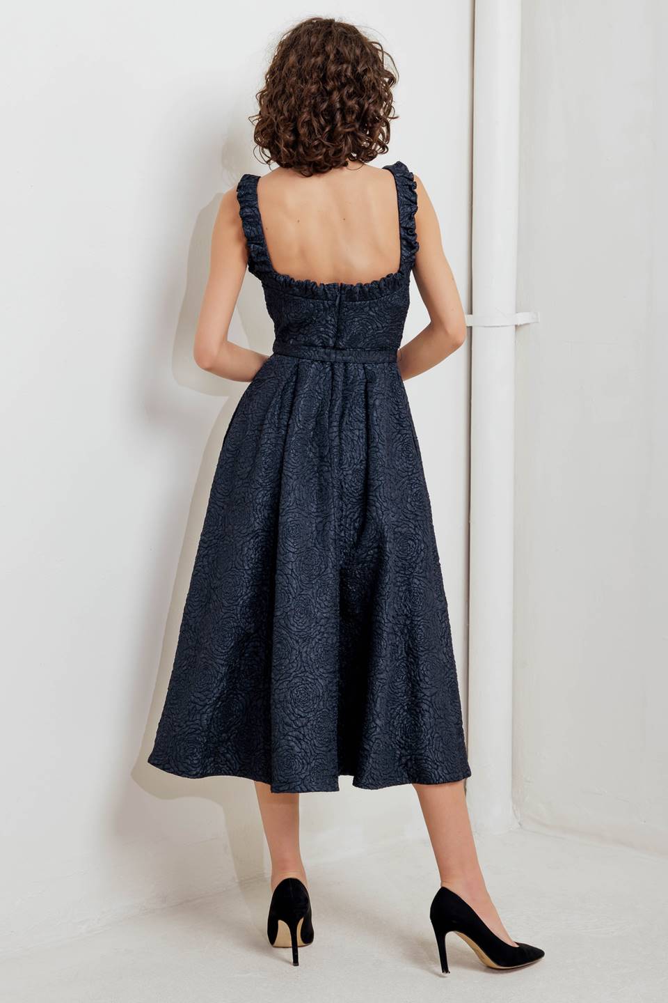 A texture woven midi dress featuring wide neckline, sleeveless with ruffled edge, self belt, full skirt low back with zipper closure