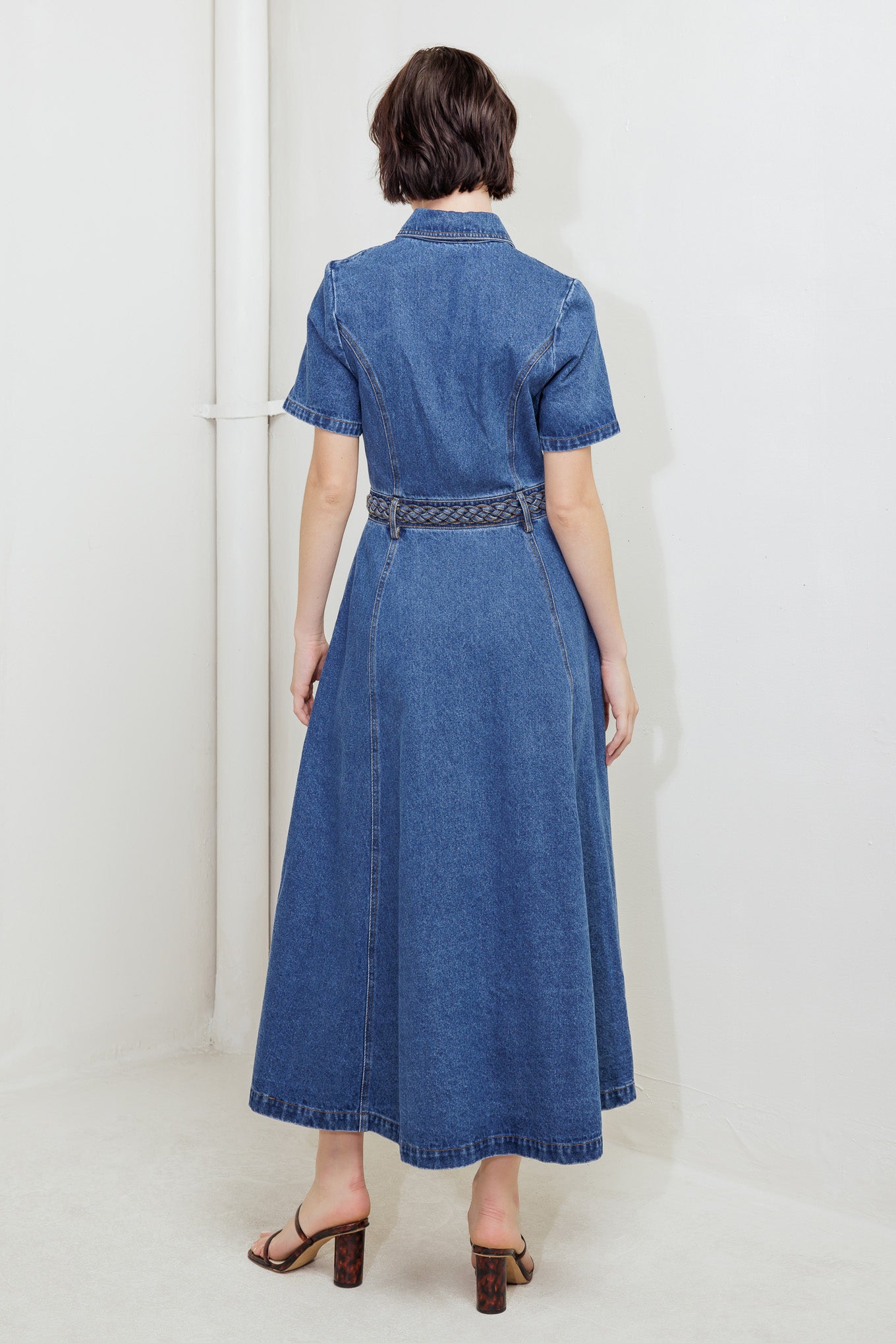 A washed denim midi dress featuring collar, short sleeve, button down, braided waistband and circle skirt