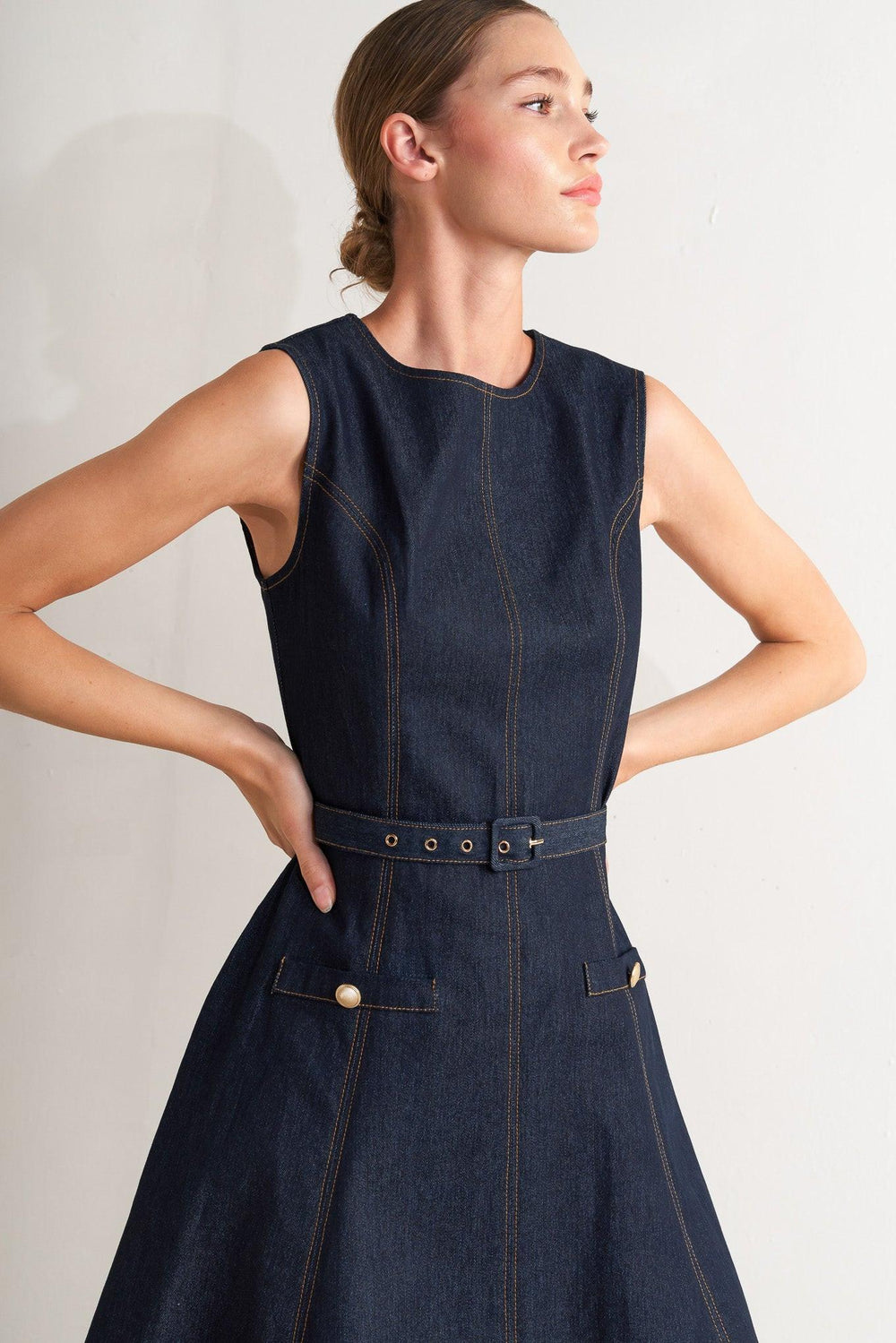 A denim midi dress featuring round neckline, sleeveless, self belt, circle skirt and back zipper closure