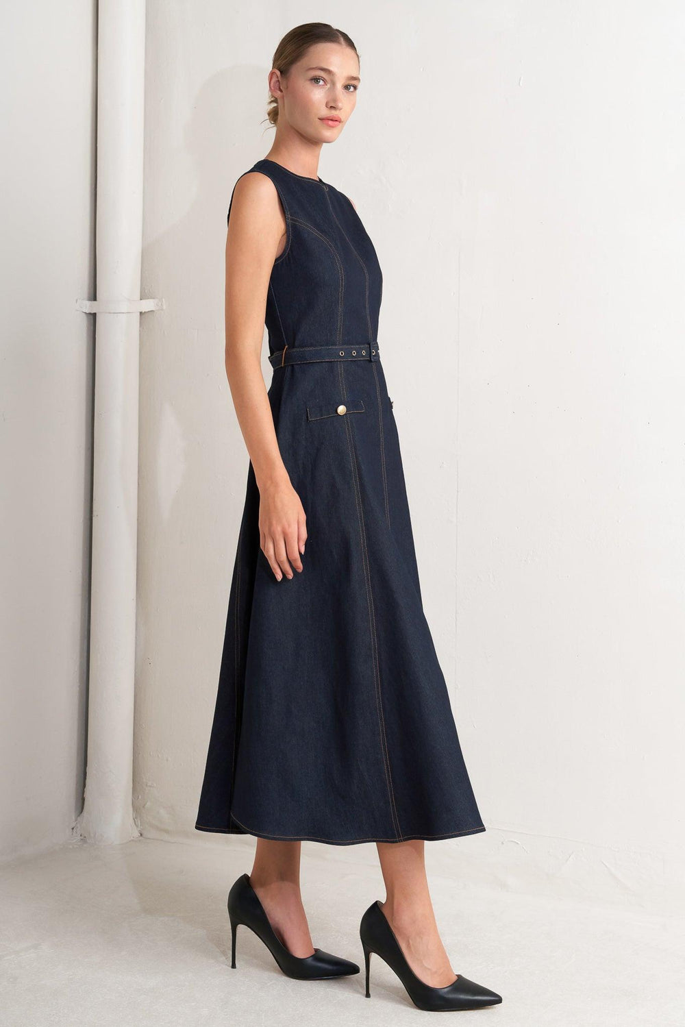 A denim midi dress featuring round neckline, sleeveless, self belt, circle skirt and back zipper closure