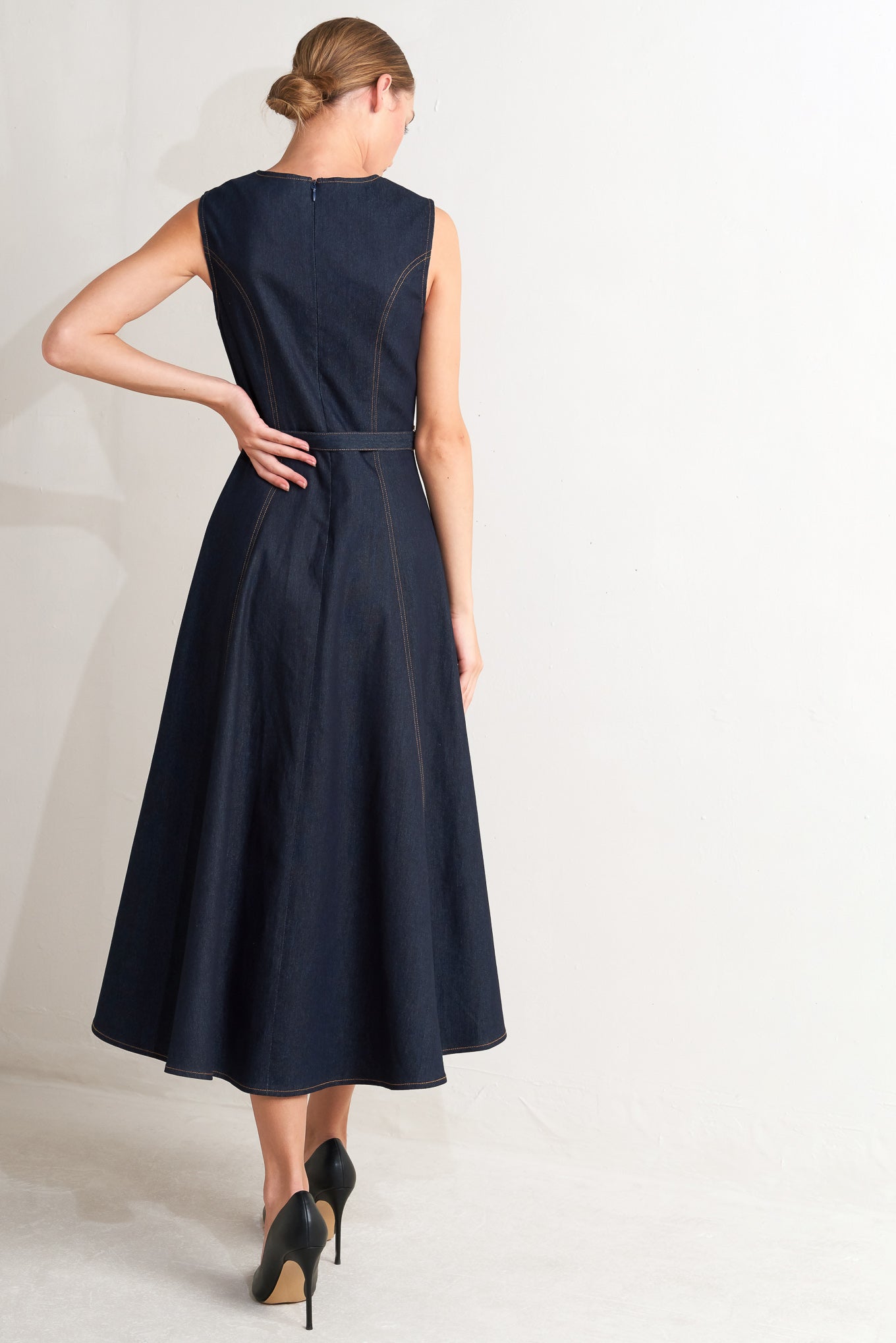 A denim midi dress featuring round neckline, sleeveless, self belt, circle skirt and back zipper closure
