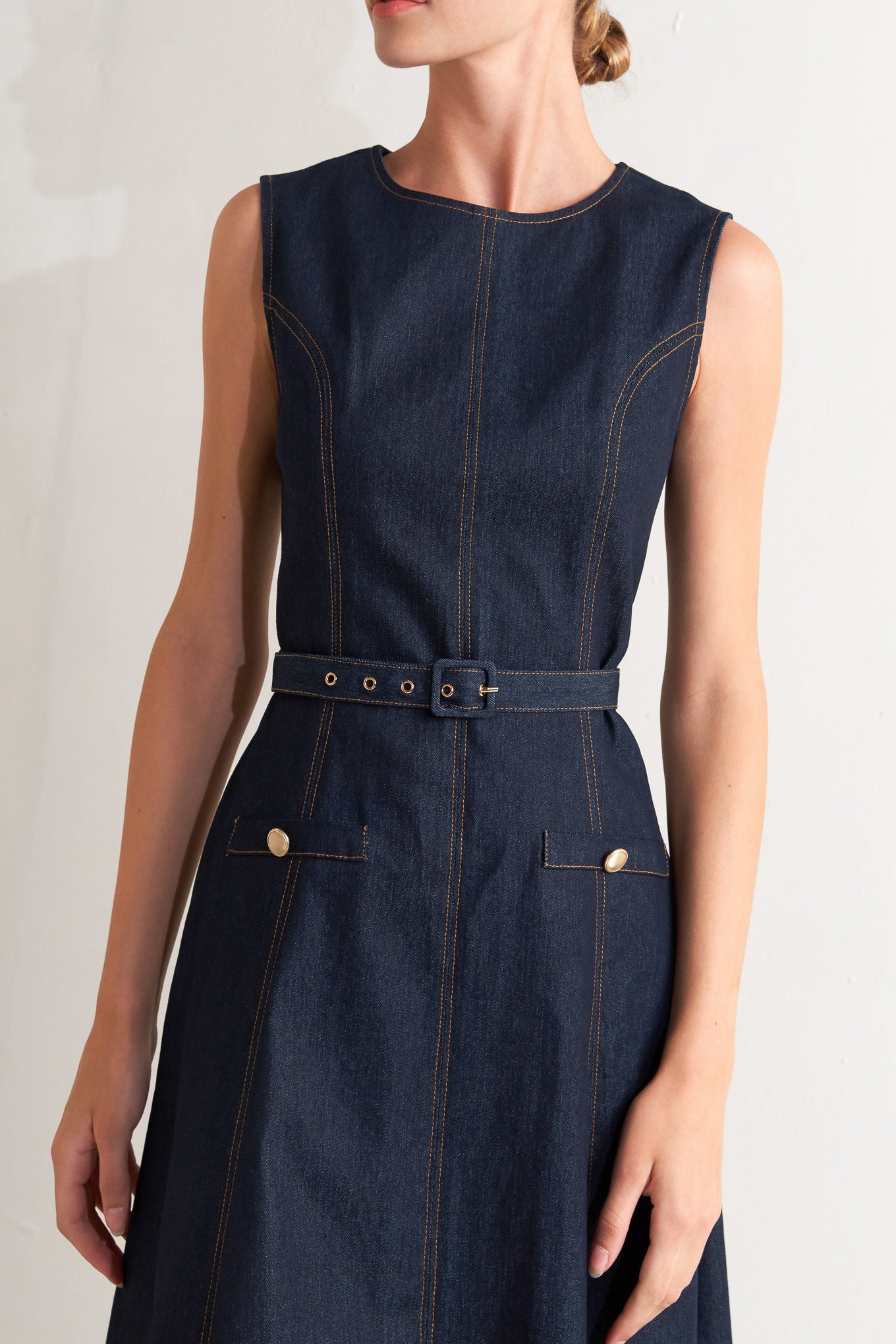 A denim midi dress featuring round neckline, sleeveless, self belt, circle skirt and back zipper closure