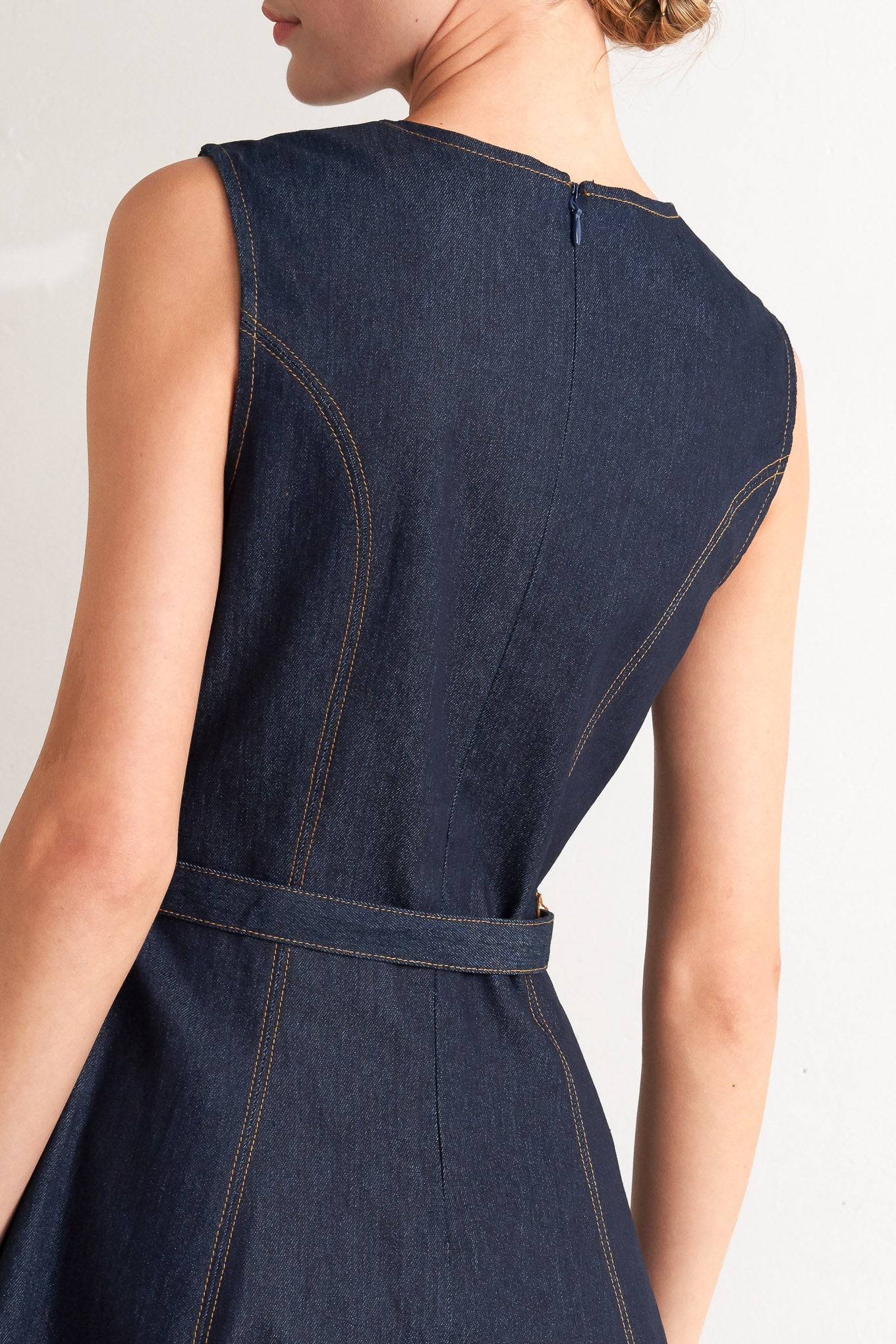 A denim midi dress featuring round neckline, sleeveless, self belt, circle skirt and back zipper closure