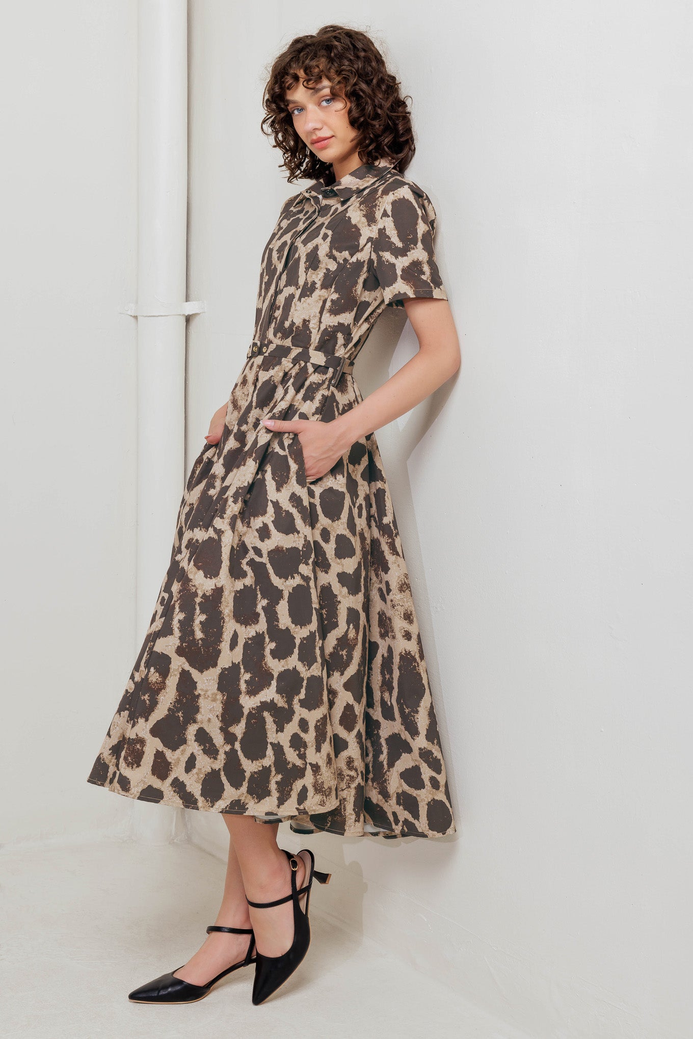 A printed woven midi dress featuring collar, short sleeve, hidden placket with button, self belt and circle skirt