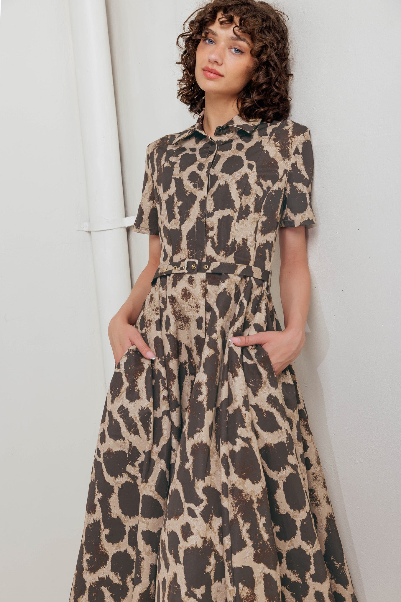A printed woven midi dress featuring collar, short sleeve, hidden placket with button, self belt and circle skirt