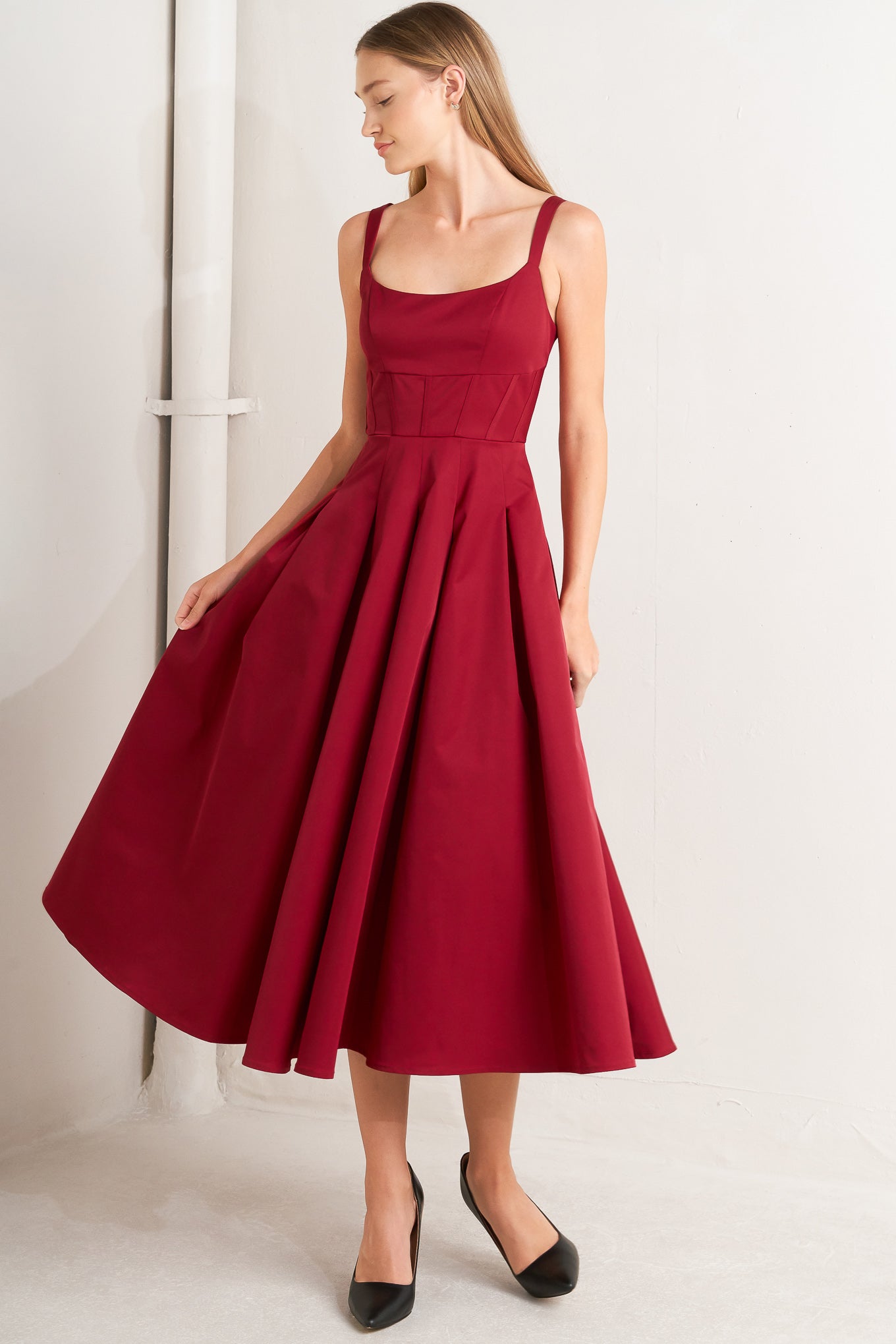 A solid woven midi dress featuring U neckline, straps, full skirt and back zipper closure