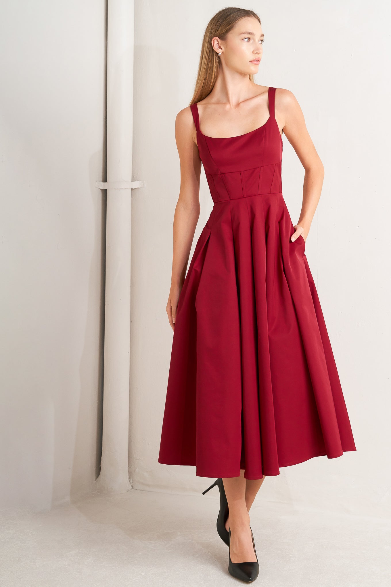 A solid woven midi dress featuring U neckline, straps, full skirt and back zipper closure