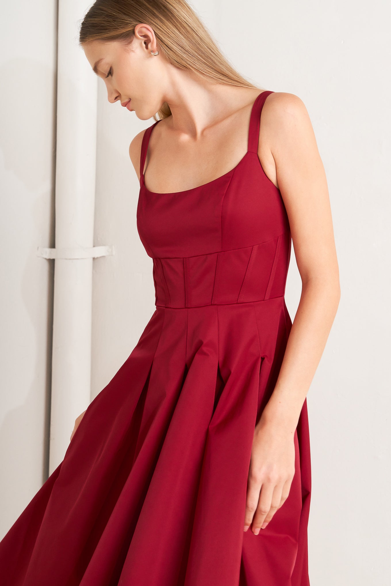 A solid woven midi dress featuring U neckline, straps, full skirt and back zipper closure