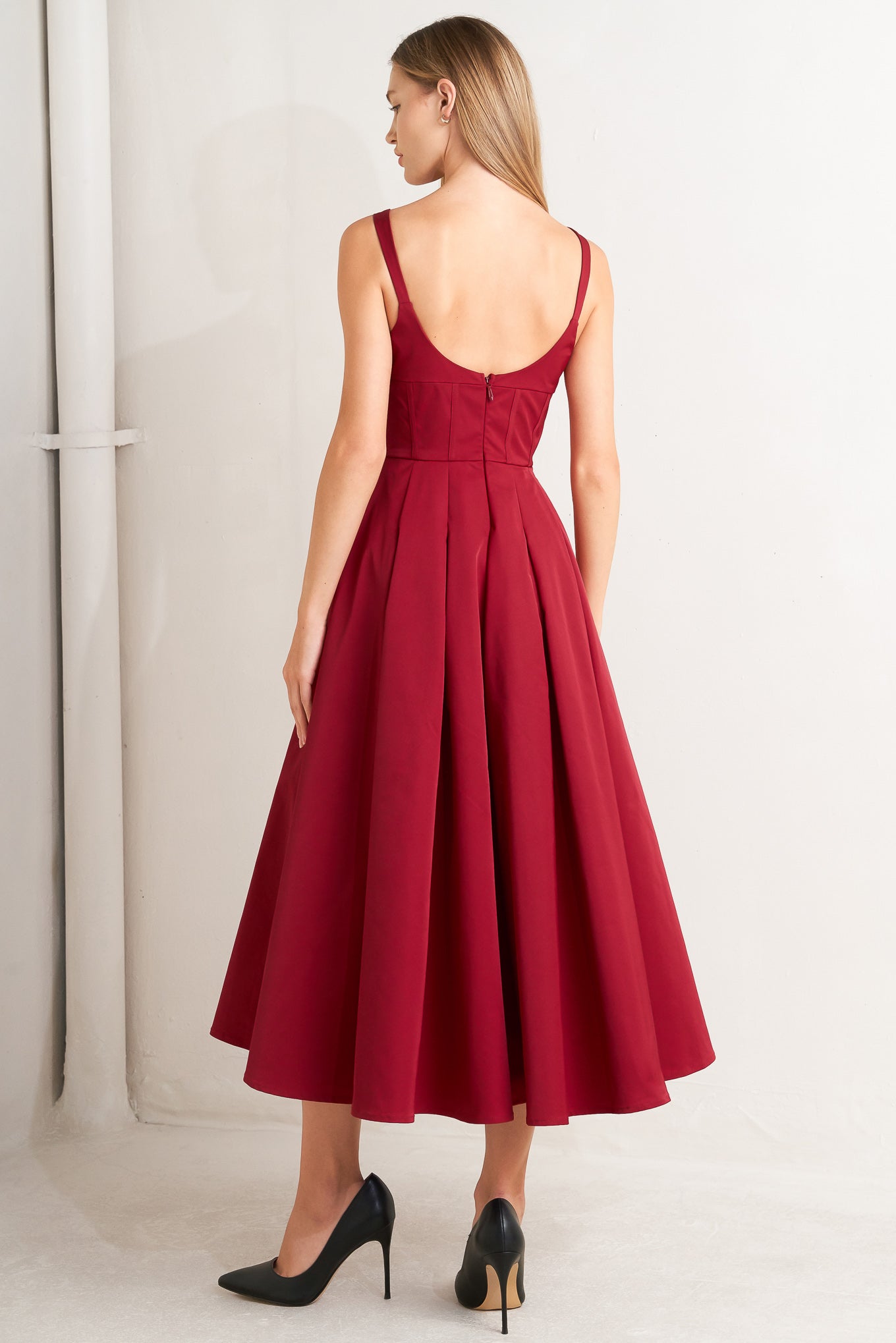 A solid woven midi dress featuring U neckline, straps, full skirt and back zipper closure