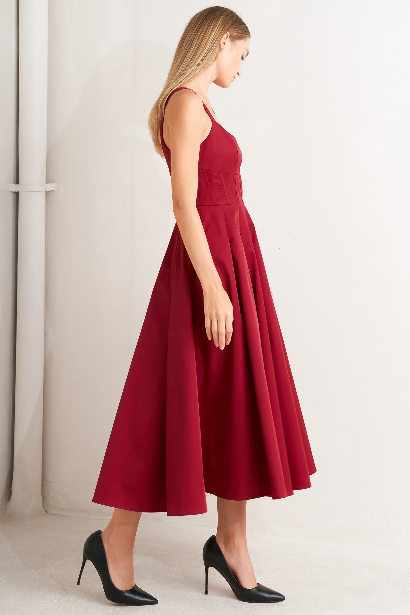 A solid woven midi dress featuring U neckline, straps, full skirt and back zipper closure