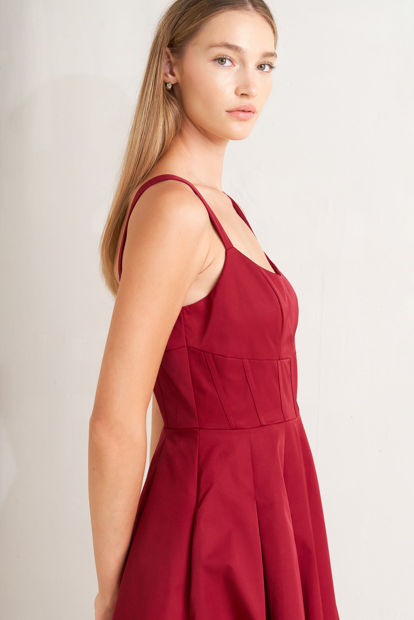 A solid woven midi dress featuring U neckline, straps, full skirt and back zipper closure