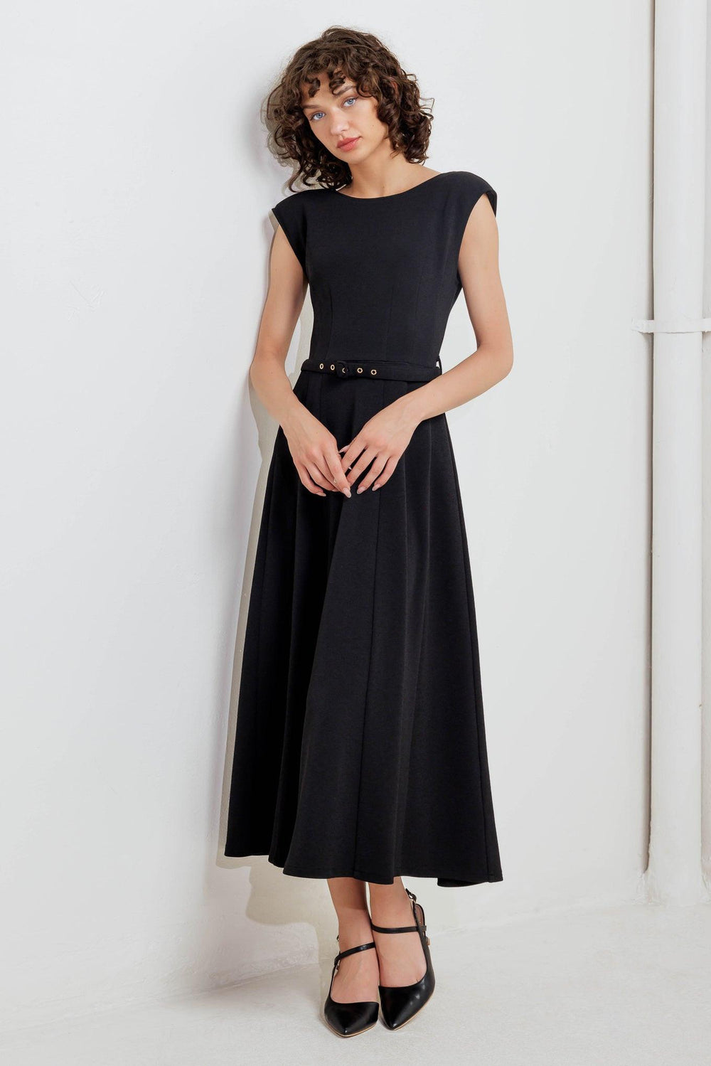 A solid woven midi dress featuring round neckline, drop shoulder, self belt, circle skirt, V back bodice and zipper closure