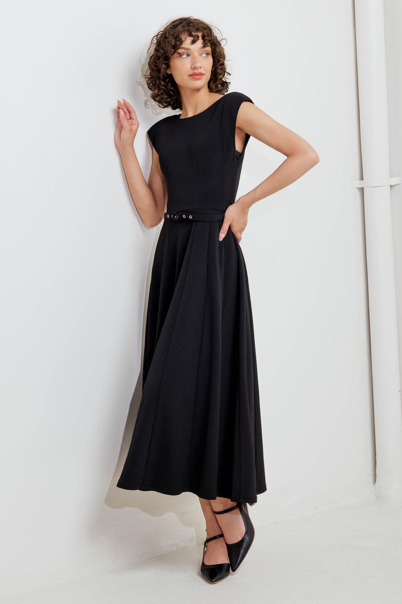 A solid woven midi dress featuring round neckline, drop shoulder, self belt, circle skirt, V back bodice and zipper closure