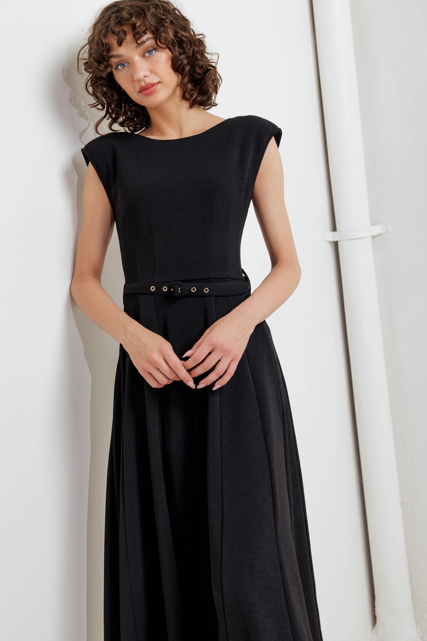 A solid woven midi dress featuring round neckline, drop shoulder, self belt, circle skirt, V back bodice and zipper closure