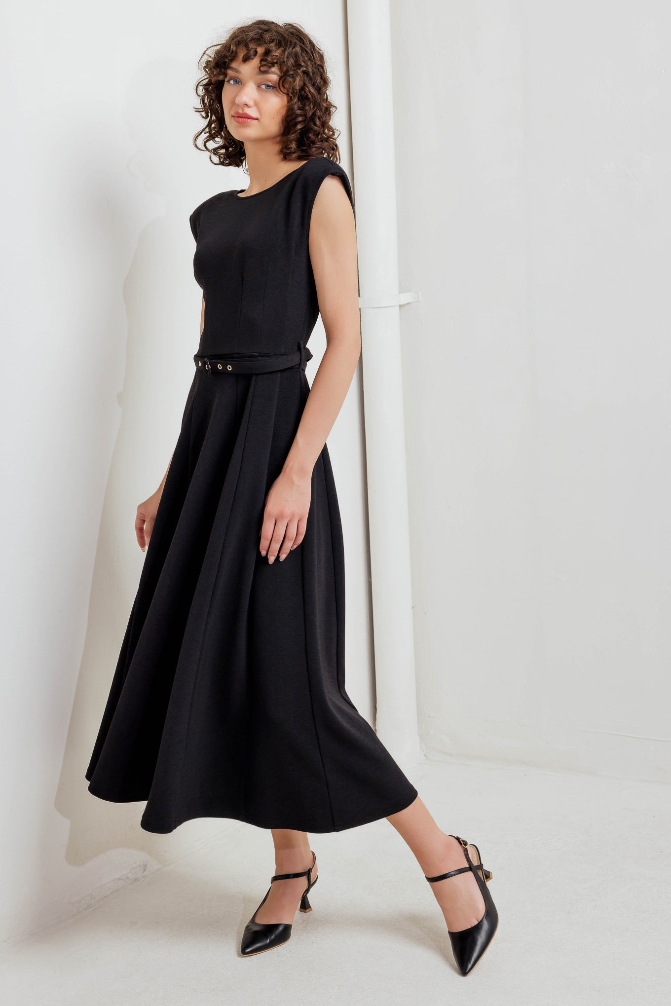 A solid woven midi dress featuring round neckline, drop shoulder, self belt, circle skirt, V back bodice and zipper closure
