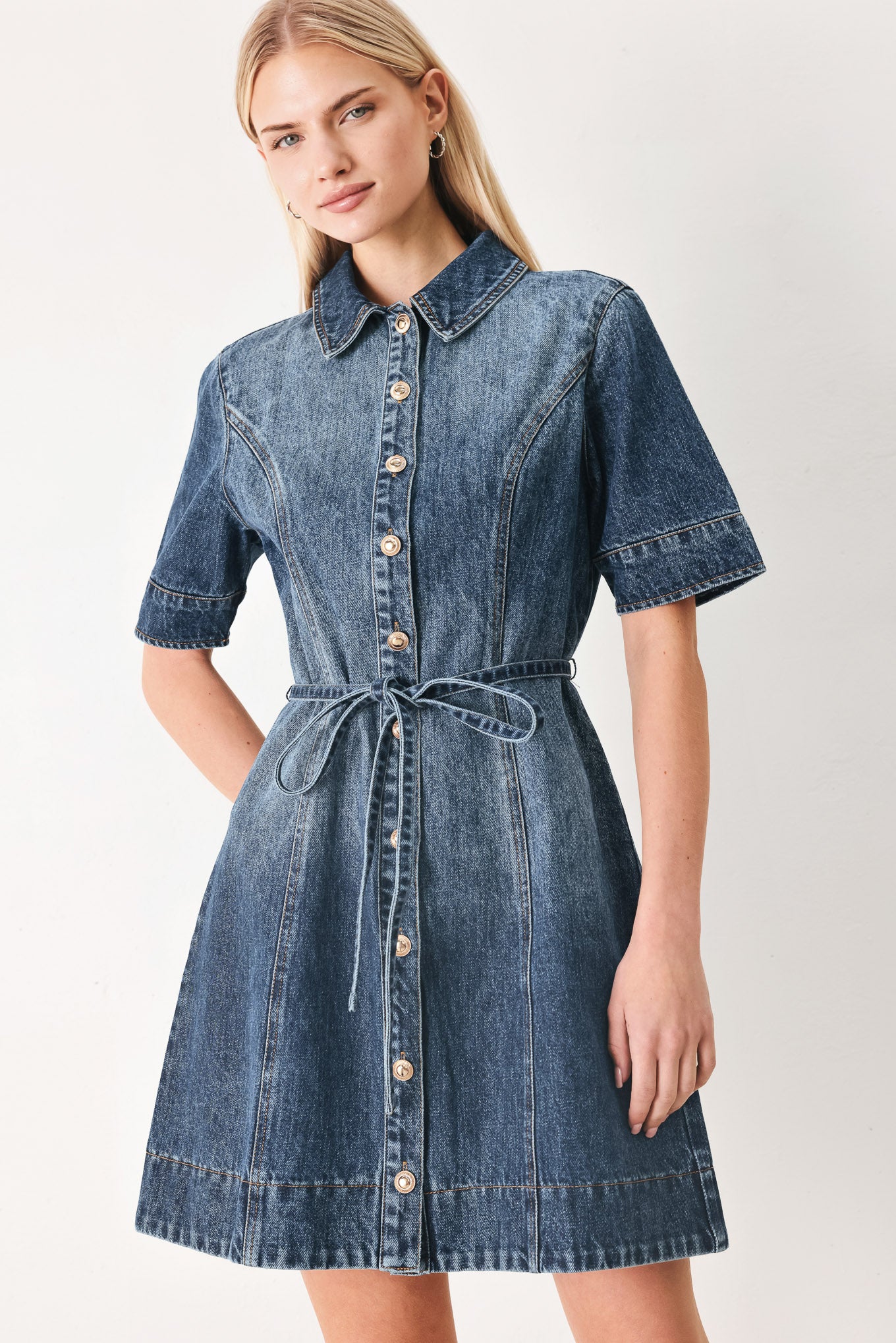 Woman wearing a denim mini dress featuring front button down, short sleeve and skinny waist tie | FREEMARKET