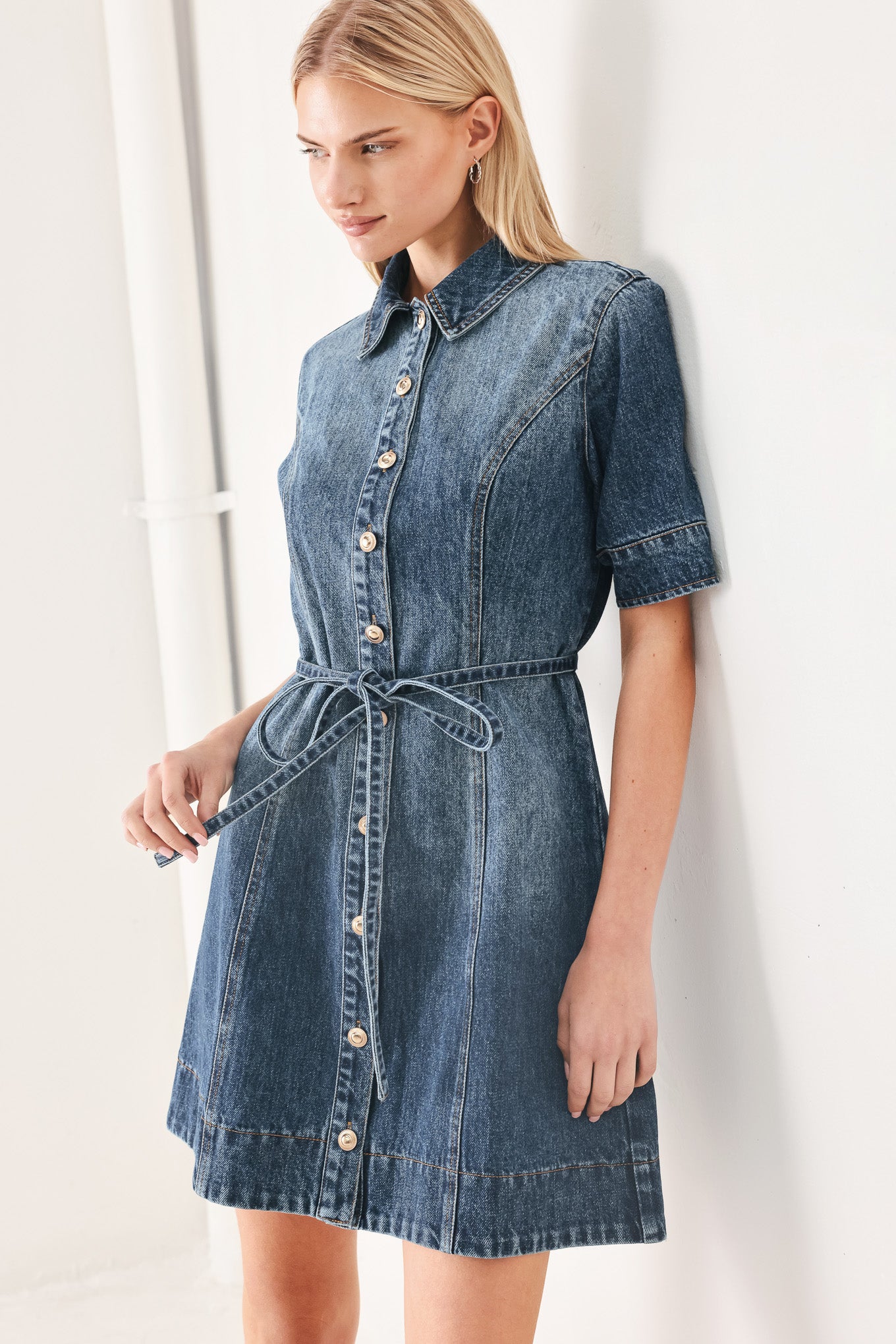 Woman wearing a denim mini dress featuring front button down, short sleeve and skinny waist tie | FREEMARKET