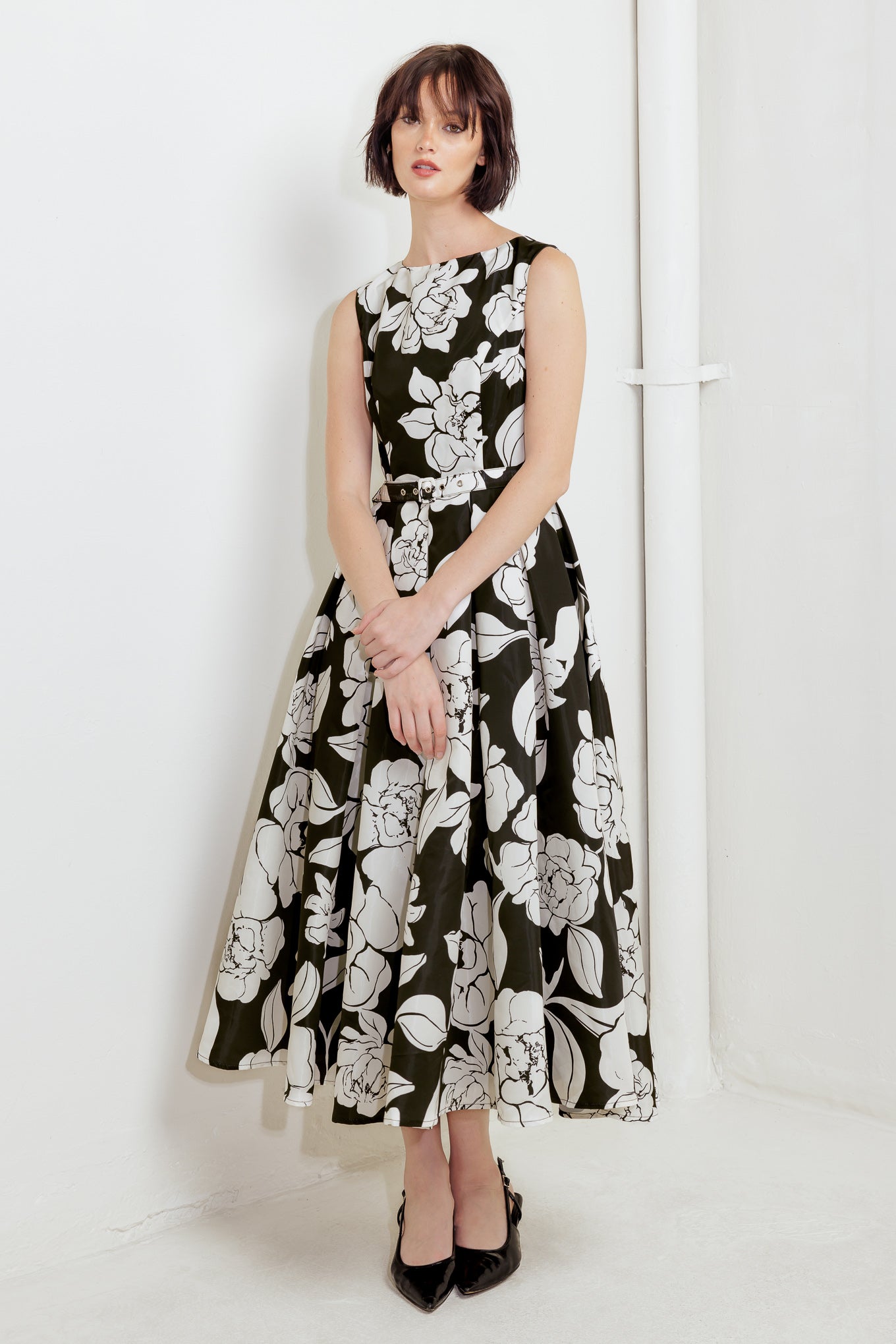 A printed woven midi dress featuring round neckline sleeveless, self belt, full skirt and back zipper closure