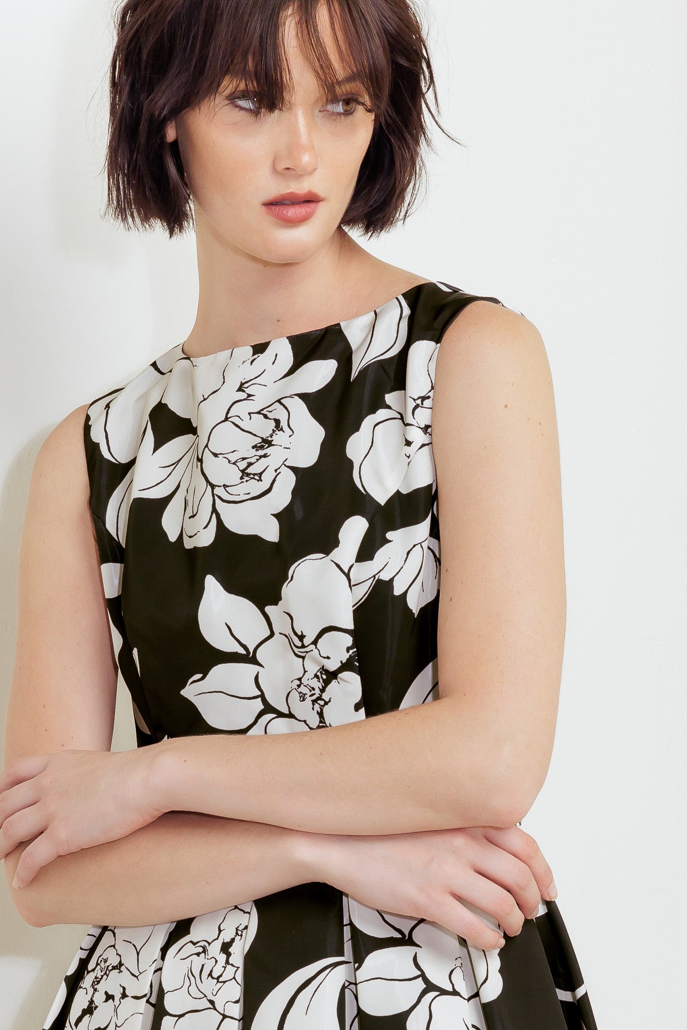 A printed woven midi dress featuring round neckline sleeveless, self belt, full skirt and back zipper closure