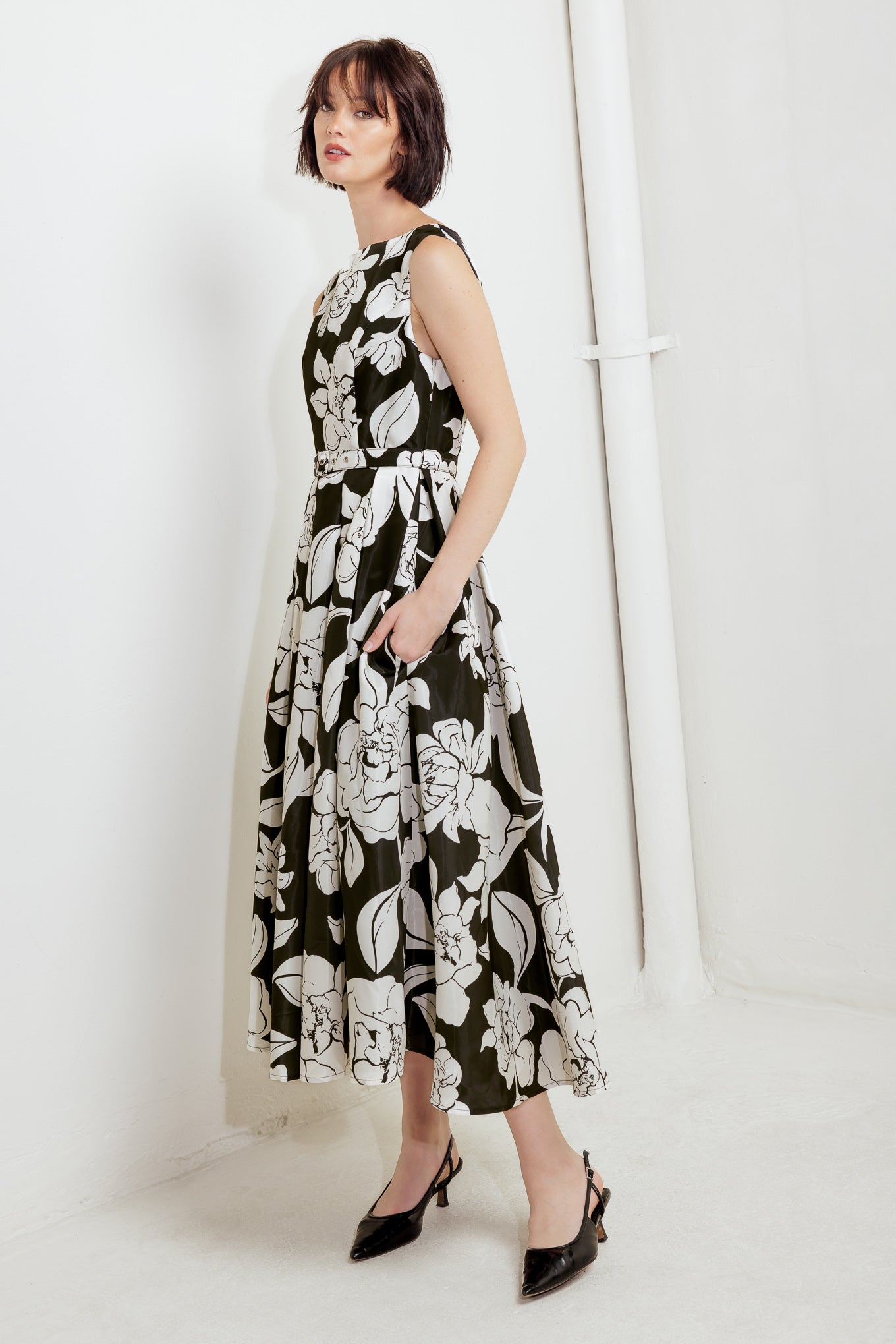 A printed woven midi dress featuring round neckline sleeveless, self belt, full skirt and back zipper closure