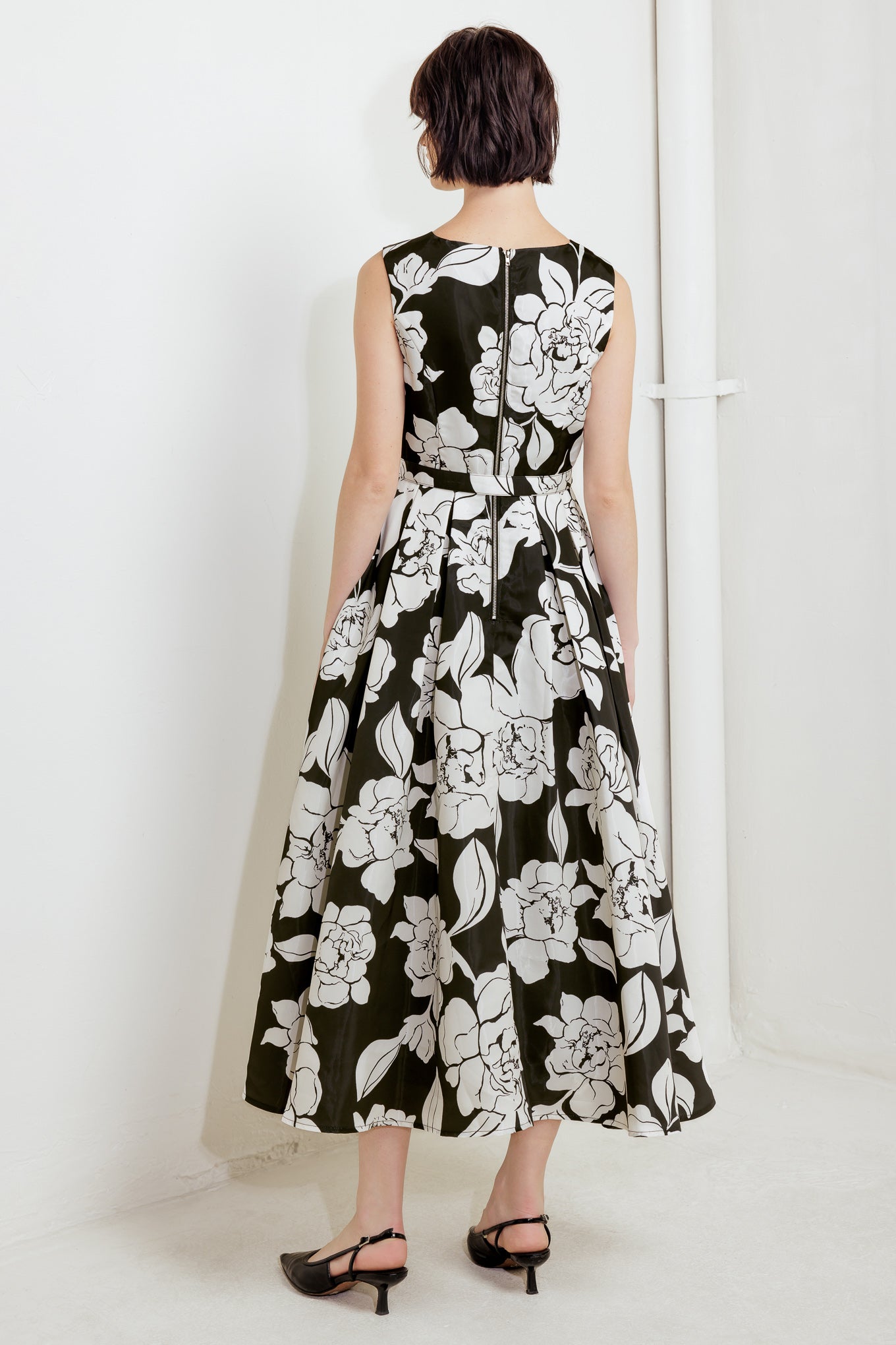 A printed woven midi dress featuring round neckline sleeveless, self belt, full skirt and back zipper closure