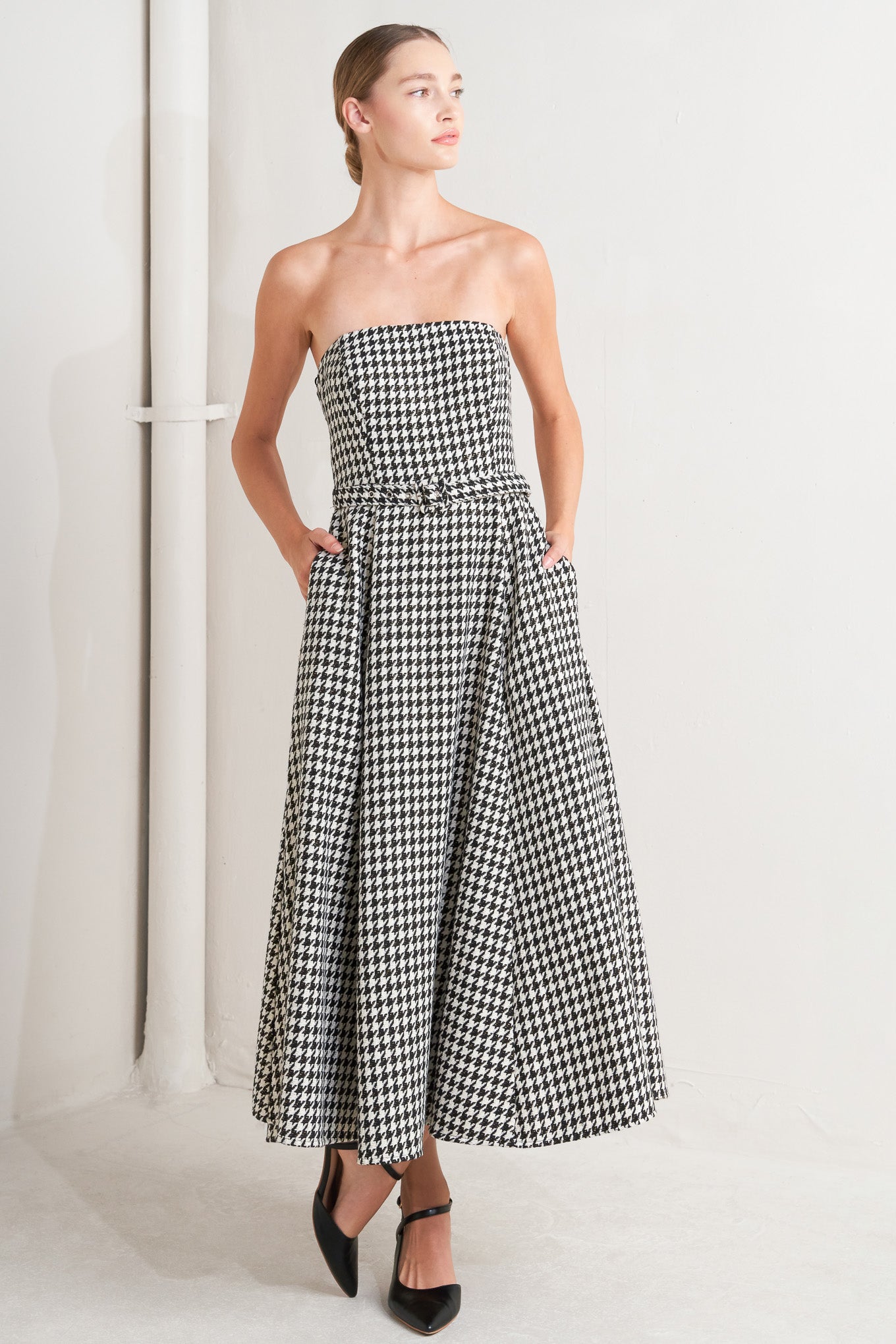 A woven houndstooth midi dress featuring strapless, self belt, full skirt and back zipper closure