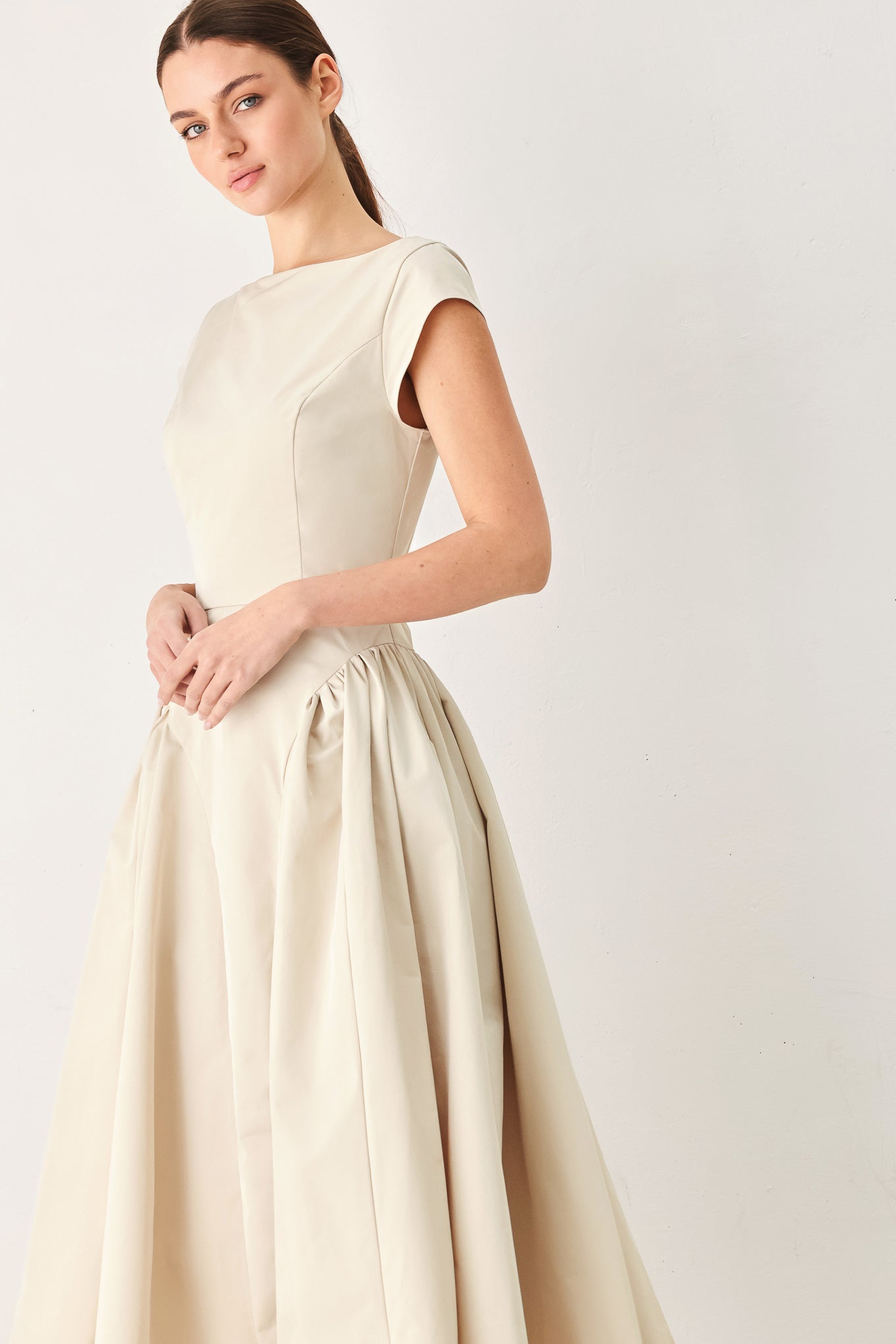Woman wearing a solid light taupe woven midi dress featuring wide neckline, cap sleeve, side shirred full skirt, back cut out and button zipper closure | FREEMARKET