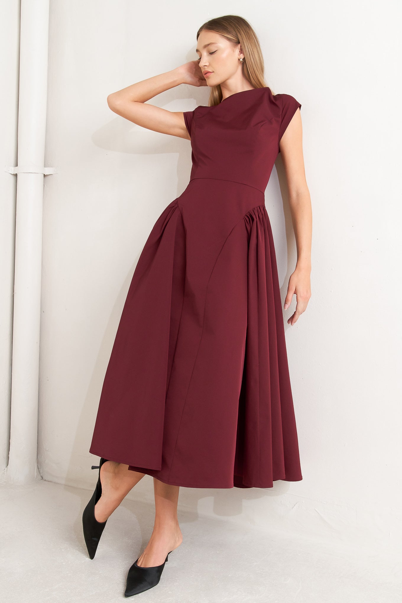 A solid woven midi dress featuring wide neckline, cap sleeve, side shirred full skirt, back cut out and button zipper closure