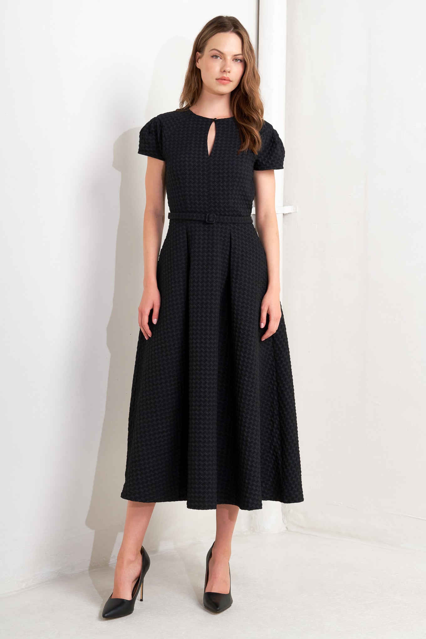 A textured woven midi dress featuring round neckline, center front button with cut out, short sleeve, full skirt, self belt and back zipper closure