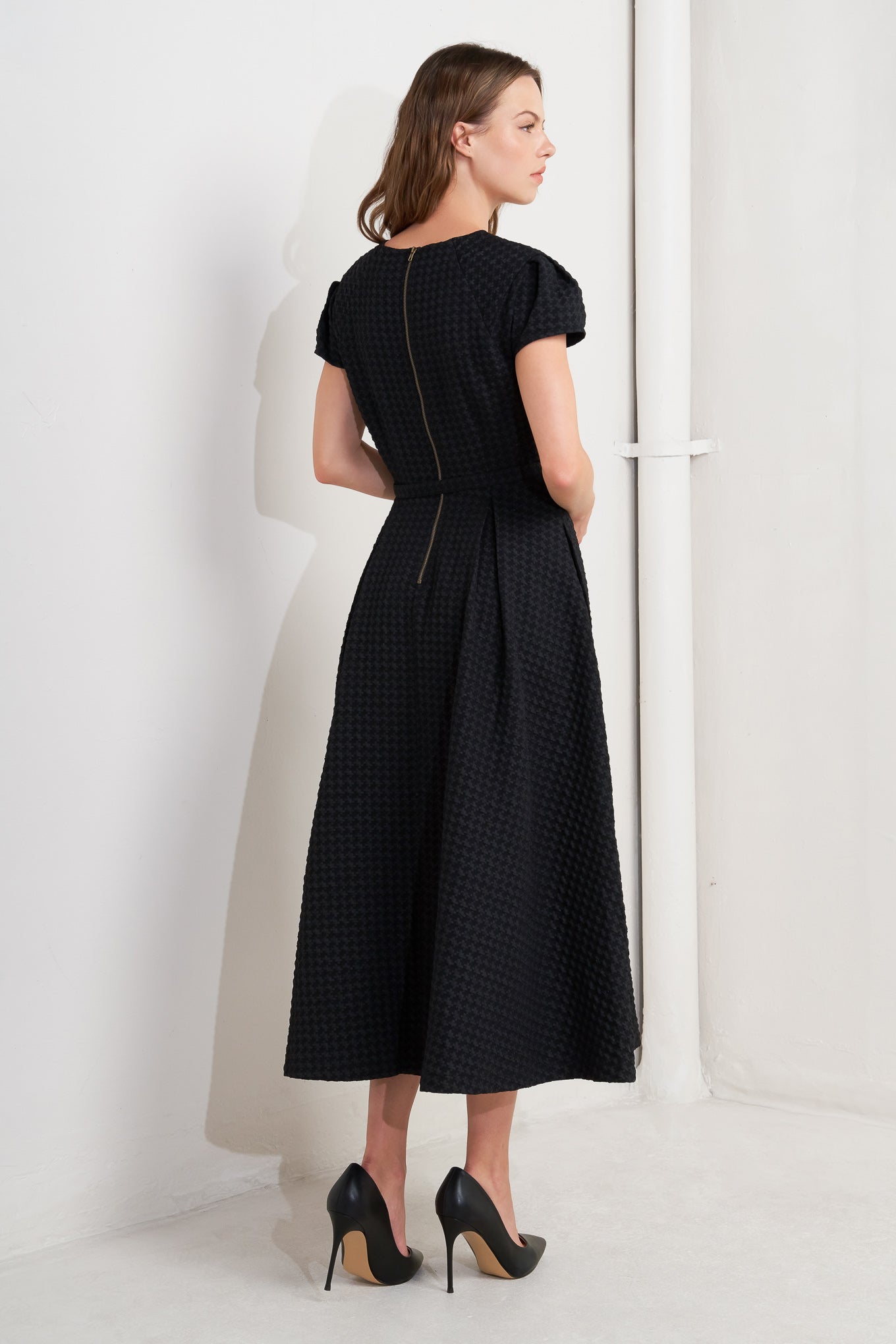 A textured woven midi dress featuring round neckline, center front button with cut out, short sleeve, full skirt, self belt and back zipper closure