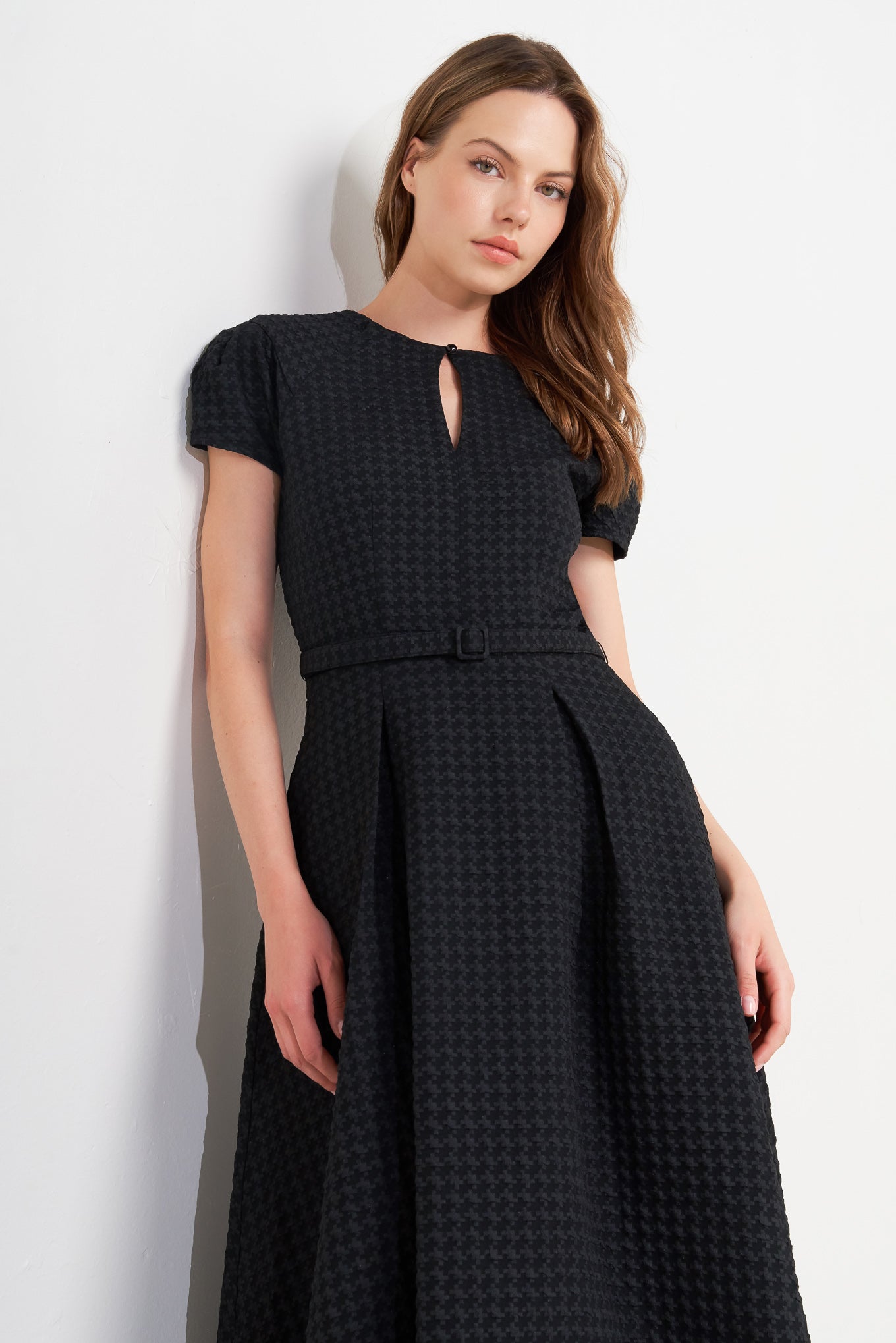 A textured woven midi dress featuring round neckline, center front button with cut out, short sleeve, full skirt, self belt and back zipper closure