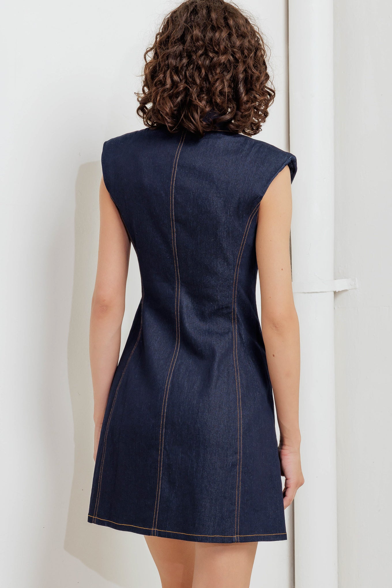A denim mini dress featuring collar, sleeveless and front button down closure