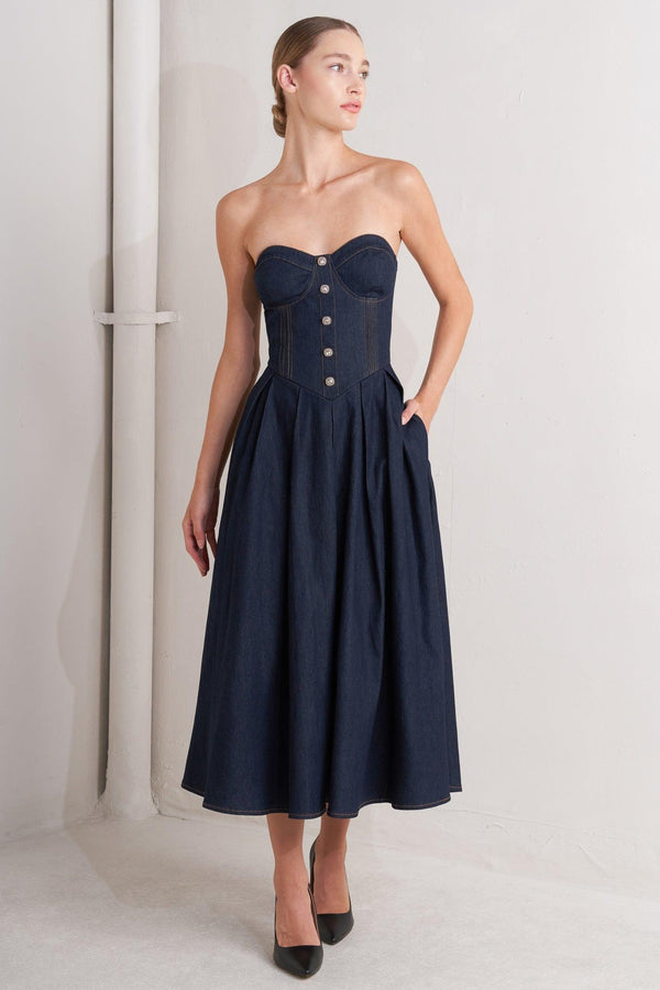 A denim midi dress featuring strapless sweetheart neckline, bustier bodice with button detail, basque waist, full skirt and back zipper closure