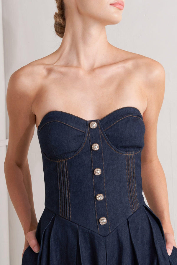 A denim midi dress featuring strapless sweetheart neckline, bustier bodice with button detail, basque waist, full skirt and back zipper closure