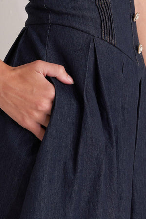 A denim midi dress featuring strapless sweetheart neckline, bustier bodice with button detail, basque waist, full skirt and back zipper closure