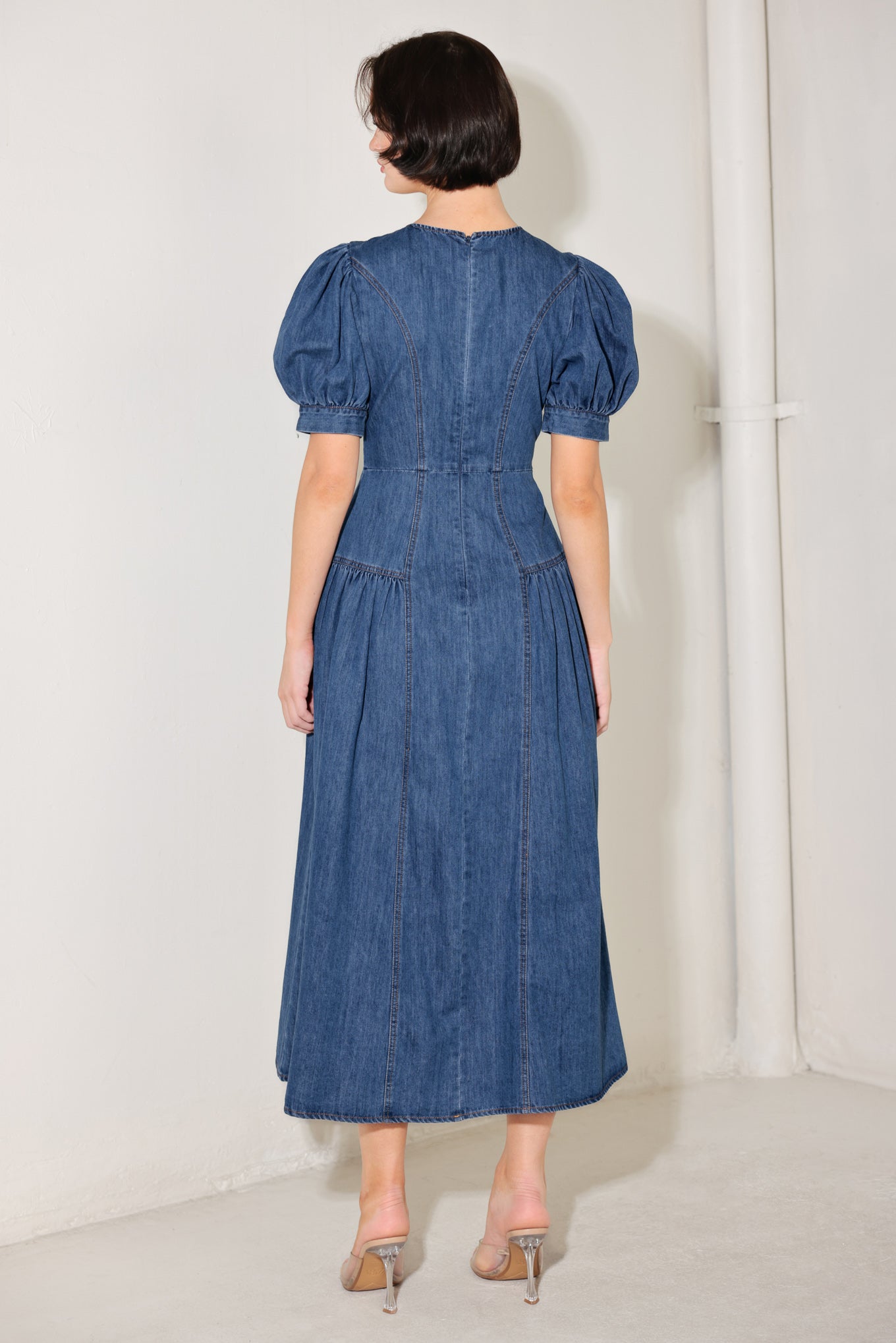 
A washed denim midi dress featuring round neckline, short puff sleeve, jewel button down, side shirring detail. full skirt and back zipper closure

Details:

Self : 85% Cotton 15% Polyester

Size &amp; Fit

- Model is 5`8" And Wearing Size Small
- Measurements Taken From Size Small
- Approx. Length: 50"