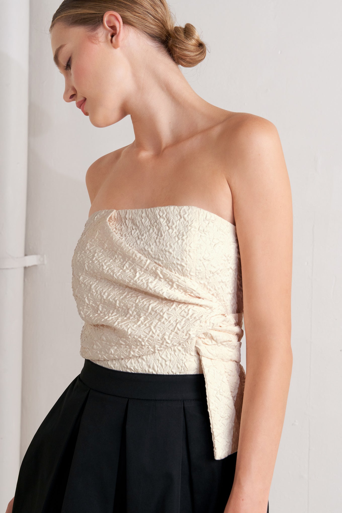A solid woven midi dress featuring strapless textured woven bodice, full skirt and back zipper closure
