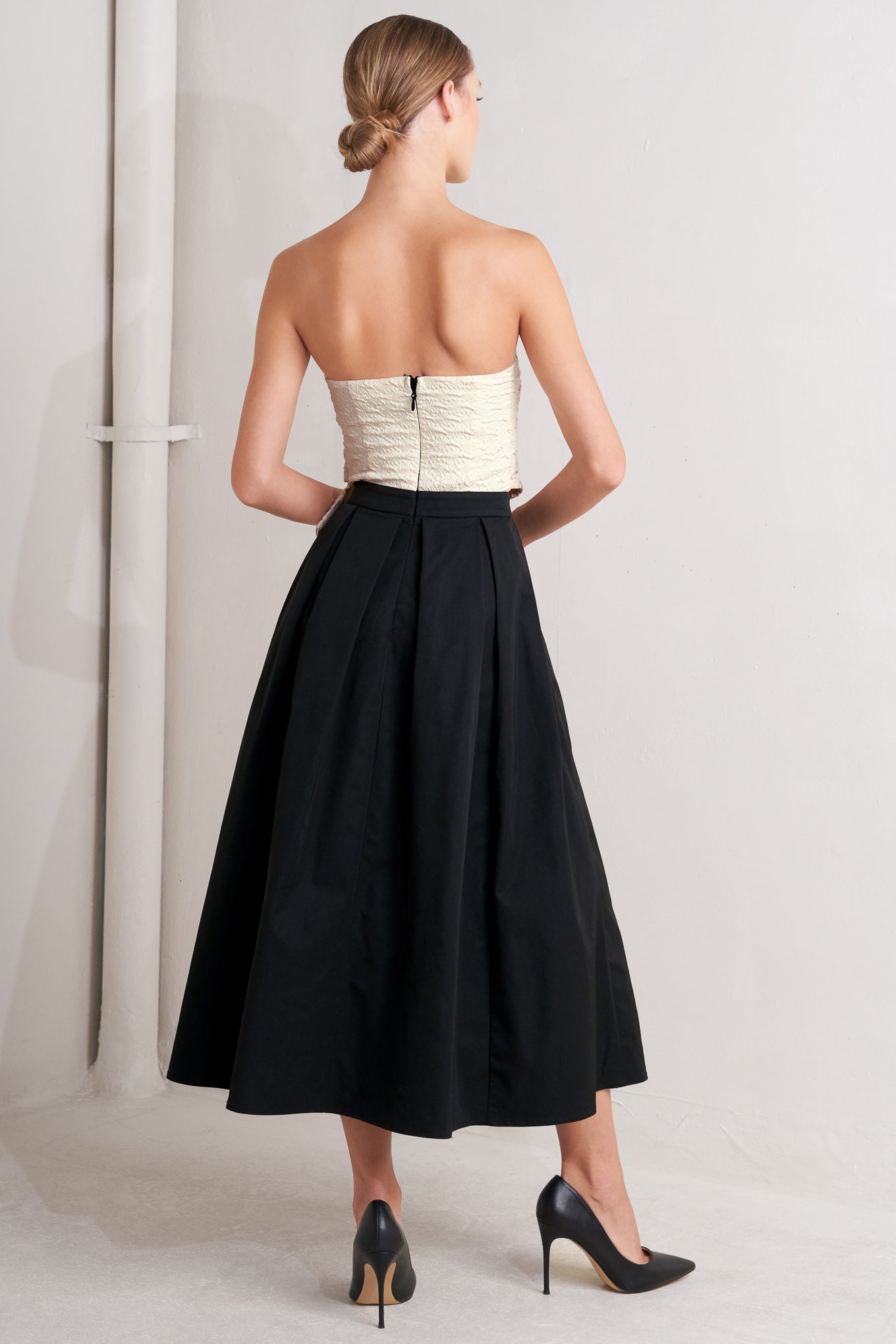 A solid woven midi dress featuring strapless textured woven bodice, full skirt and back zipper closure