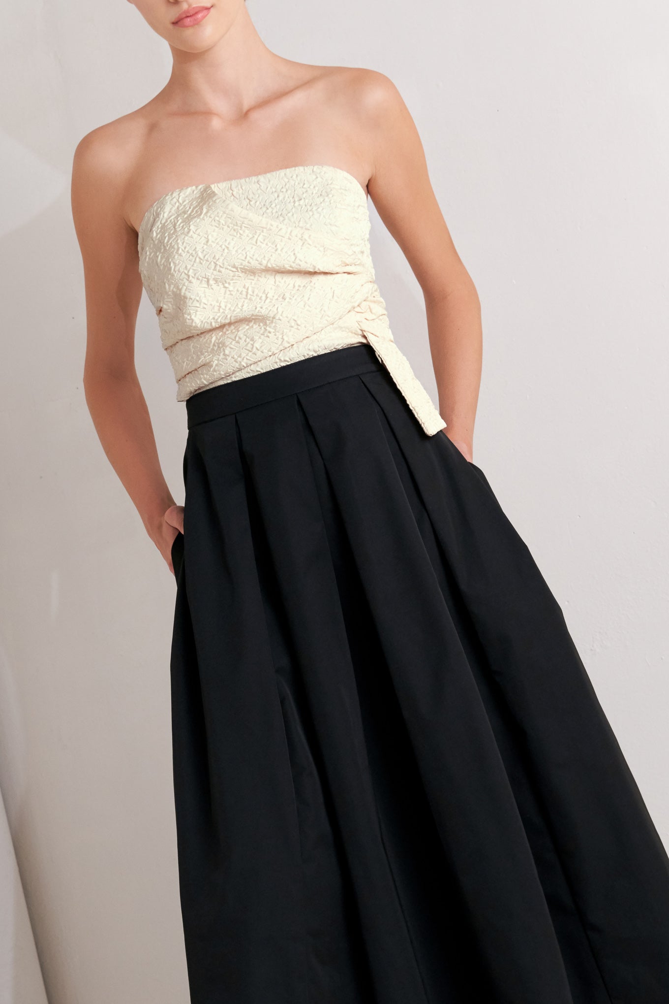 A solid woven midi dress featuring strapless textured woven bodice, full skirt and back zipper closure