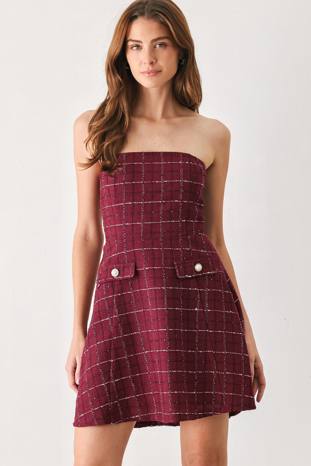 A woman modeling a strapless tube dress in a deep wine burgundy red plaid tweed fabric with white windowpane lines and two decorative buttons on the front | FREEMARKET